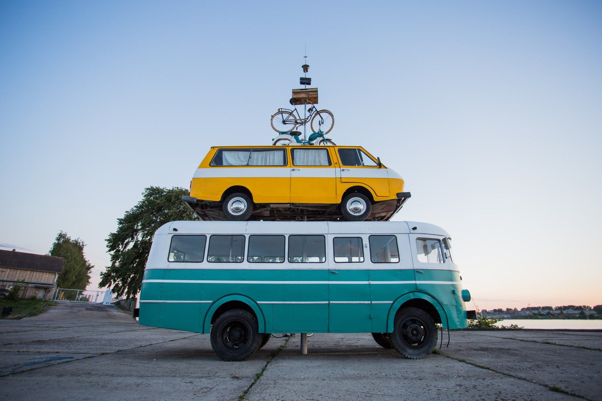 A green bus with a yellow van on top of it.
