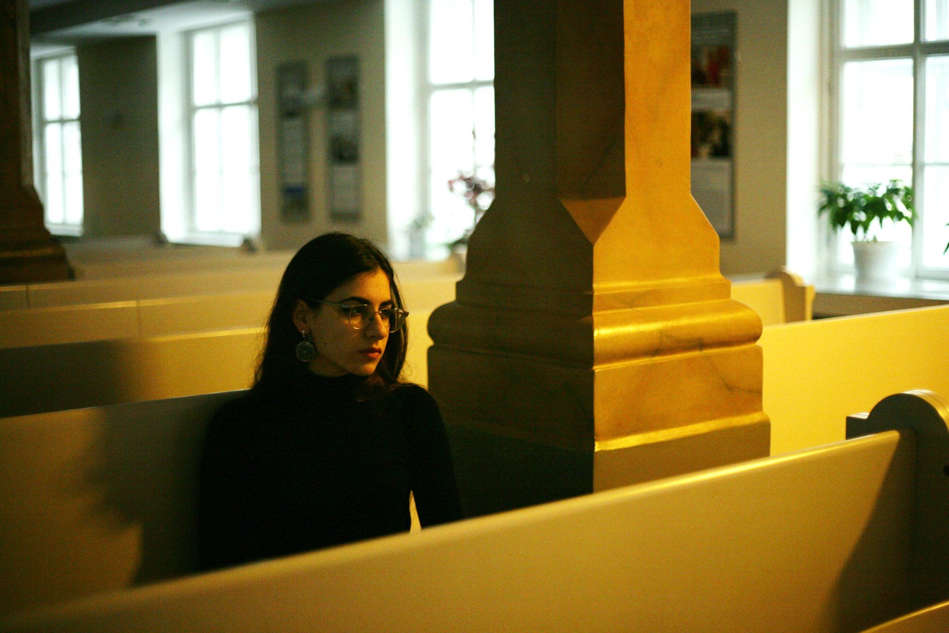 A woman sits in a row of benches in a church