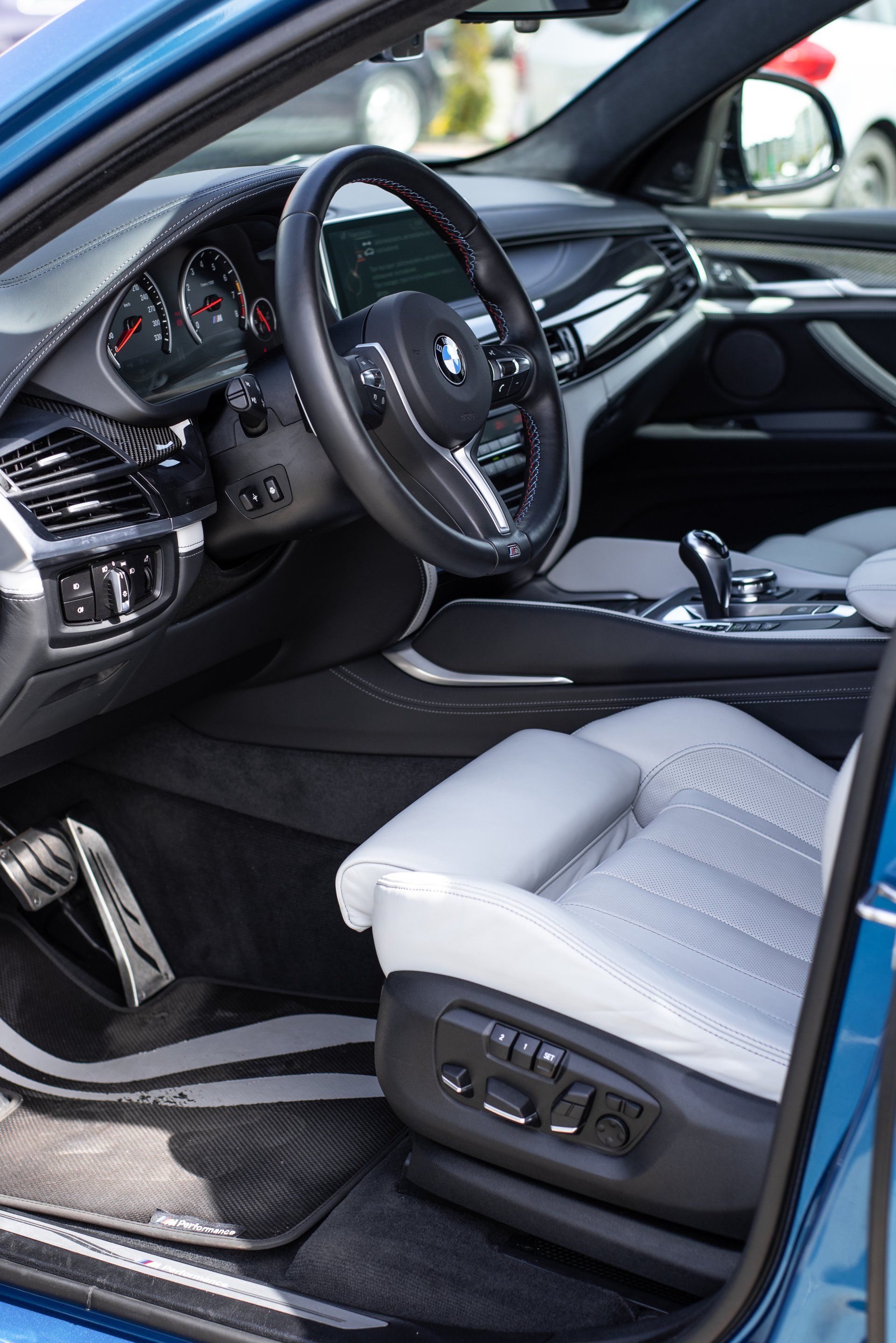 Blauw BMW-interieur met witte lederen stoelen en zwart dashboard.