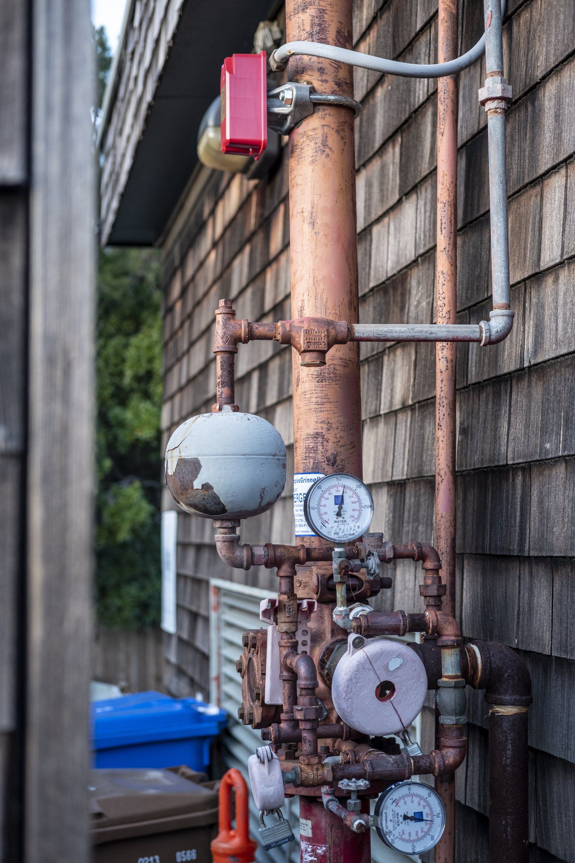 A bunch of pipes and gauges on the side of a building