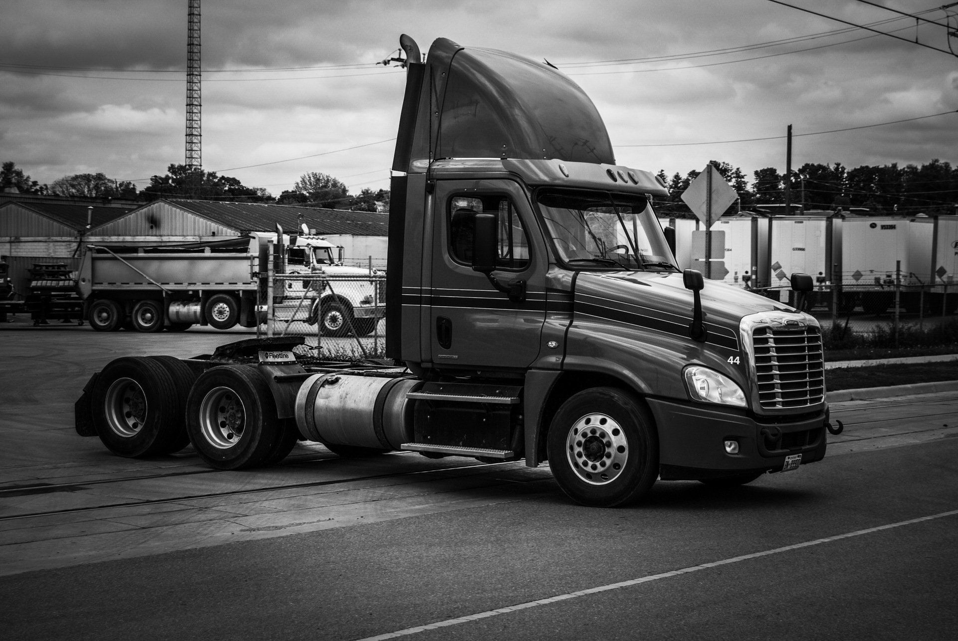 A black and white photo of a semi truck on the road.