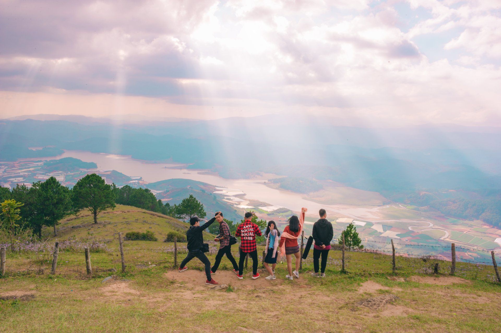 A group of people are standing on top of a grassy hill.