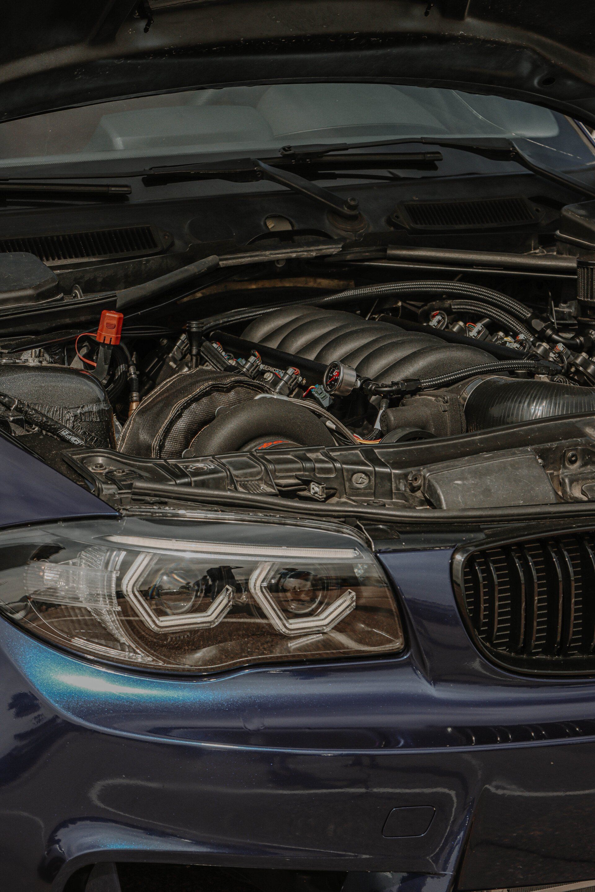 Blue BMW with hood open, revealing engine.