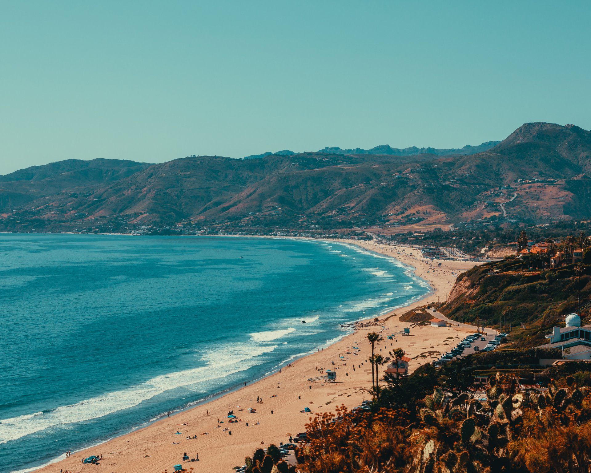 An aerial view of a beach with mountains in the background.