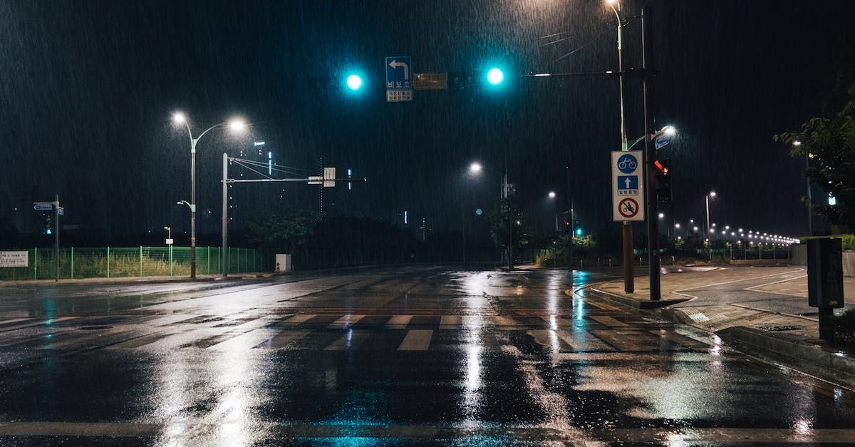 A wet street at night with a traffic light in the background.