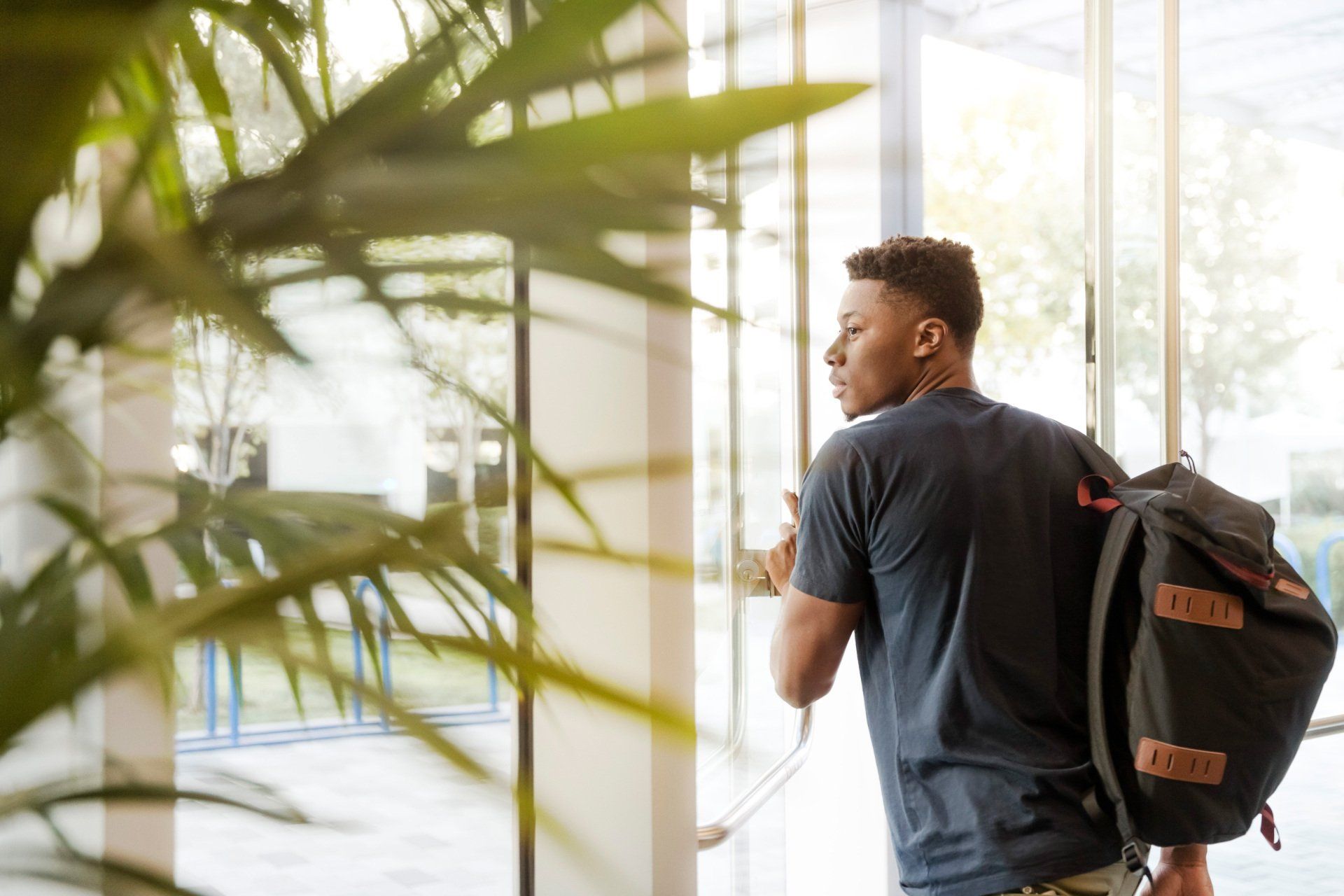 young male student walking with a bag on his back