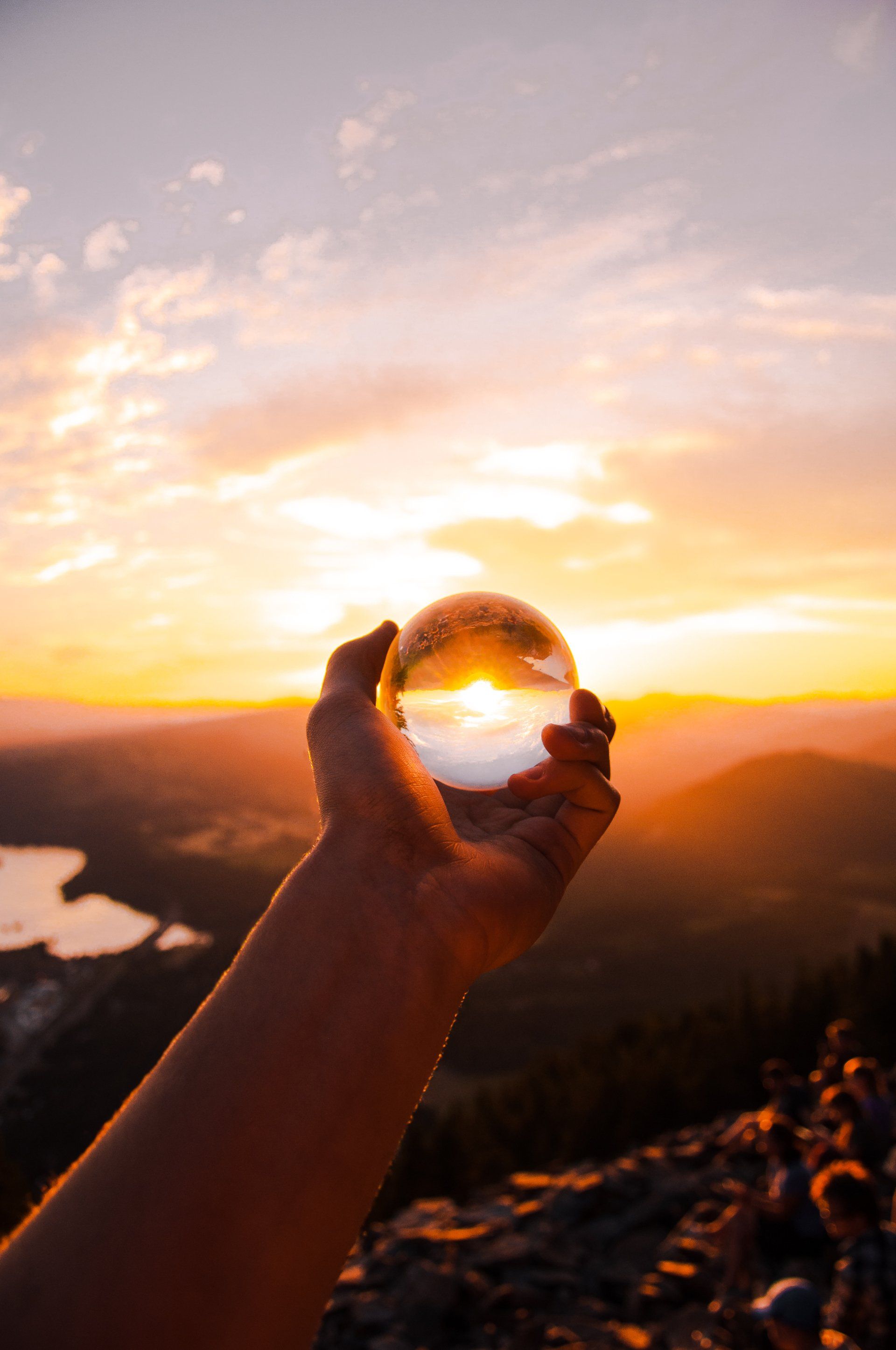 hand holding large glass ball sun sky