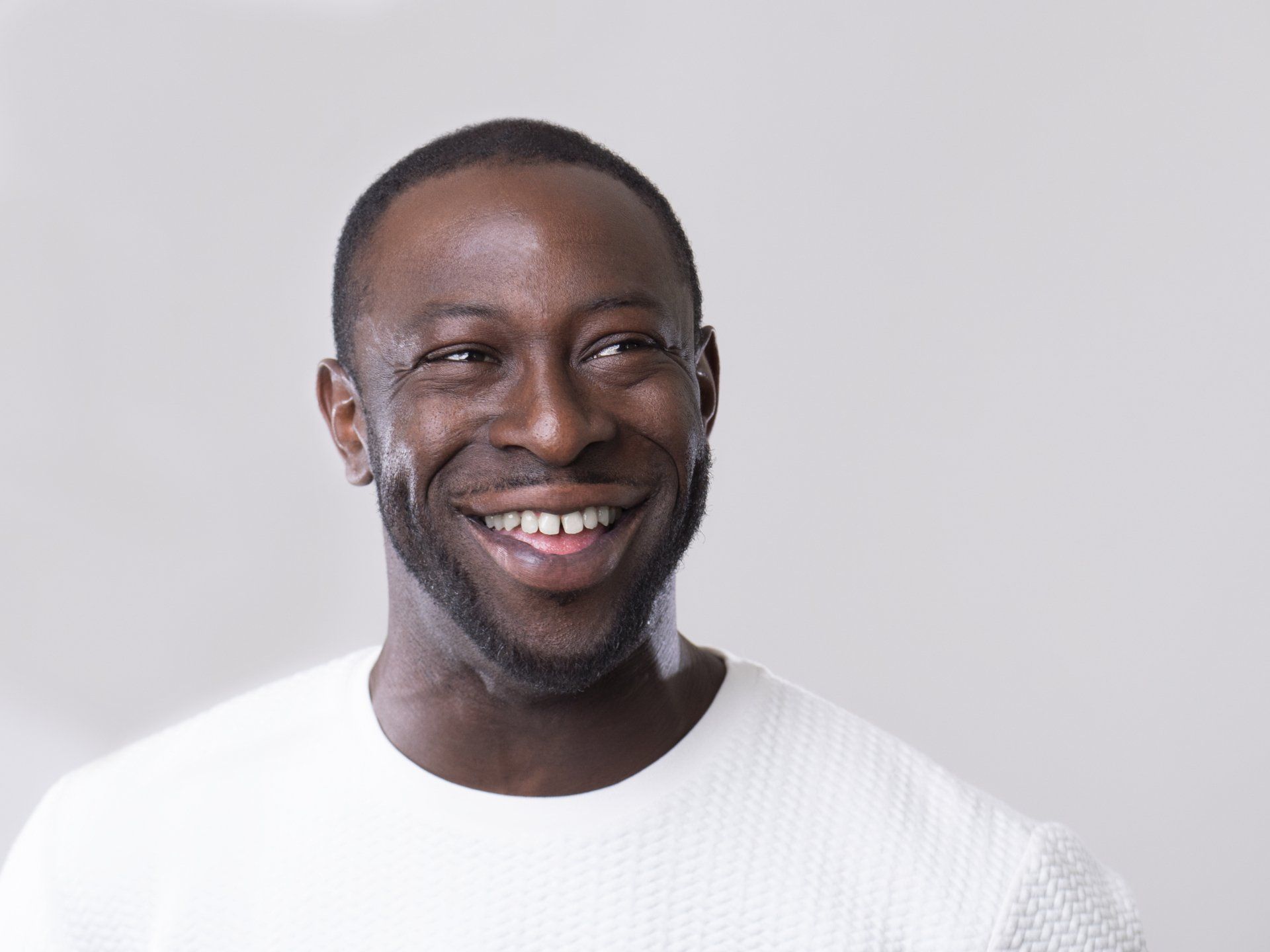 Smiling man in a white shirt against a light gray background