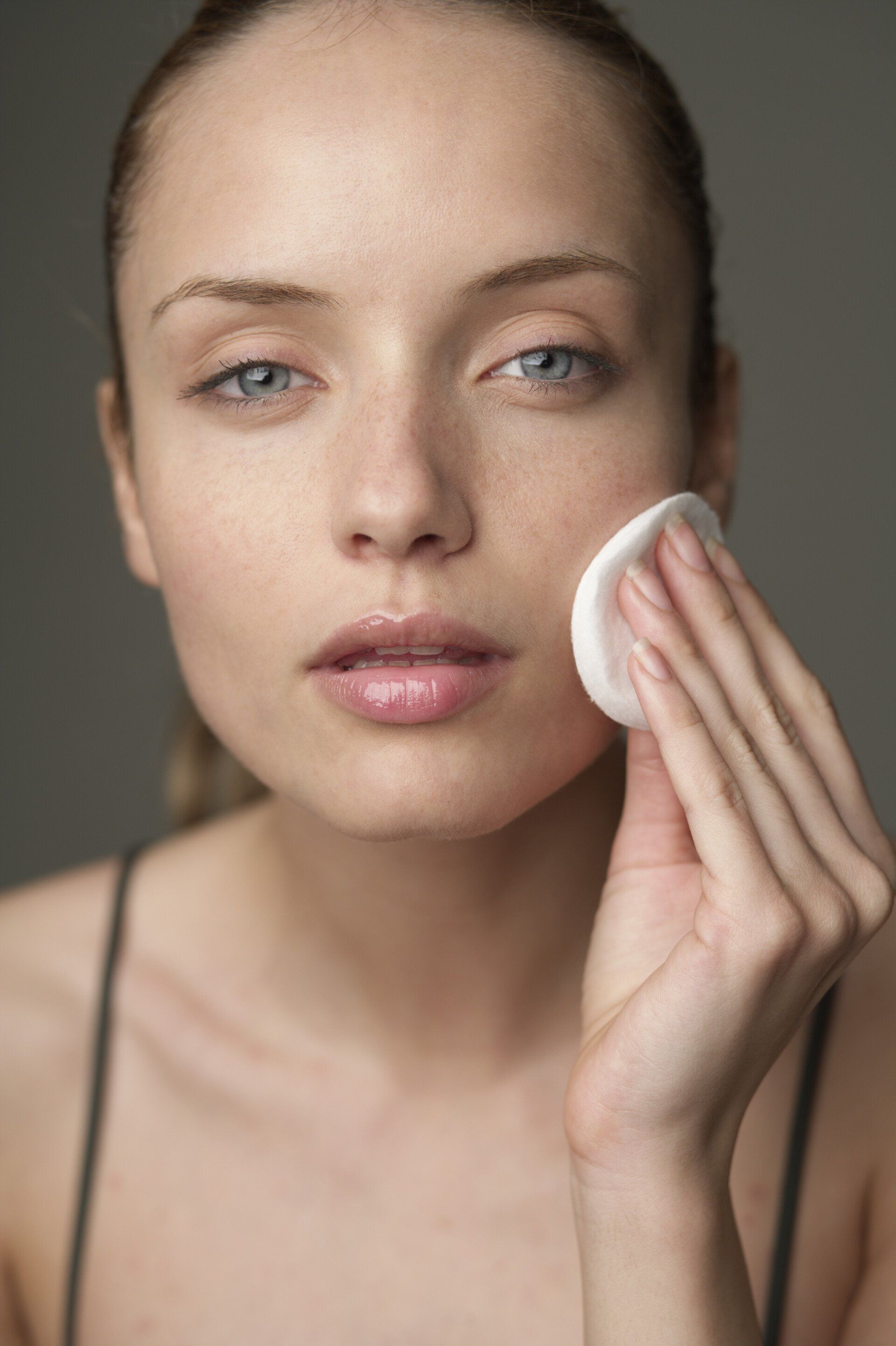 a woman is cleaning her face with a cotton pad .