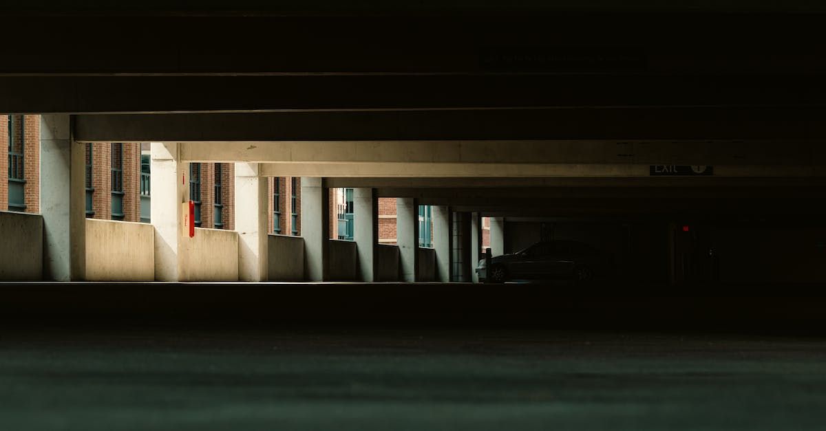 A dark parking garage with a lot of windows and columns.