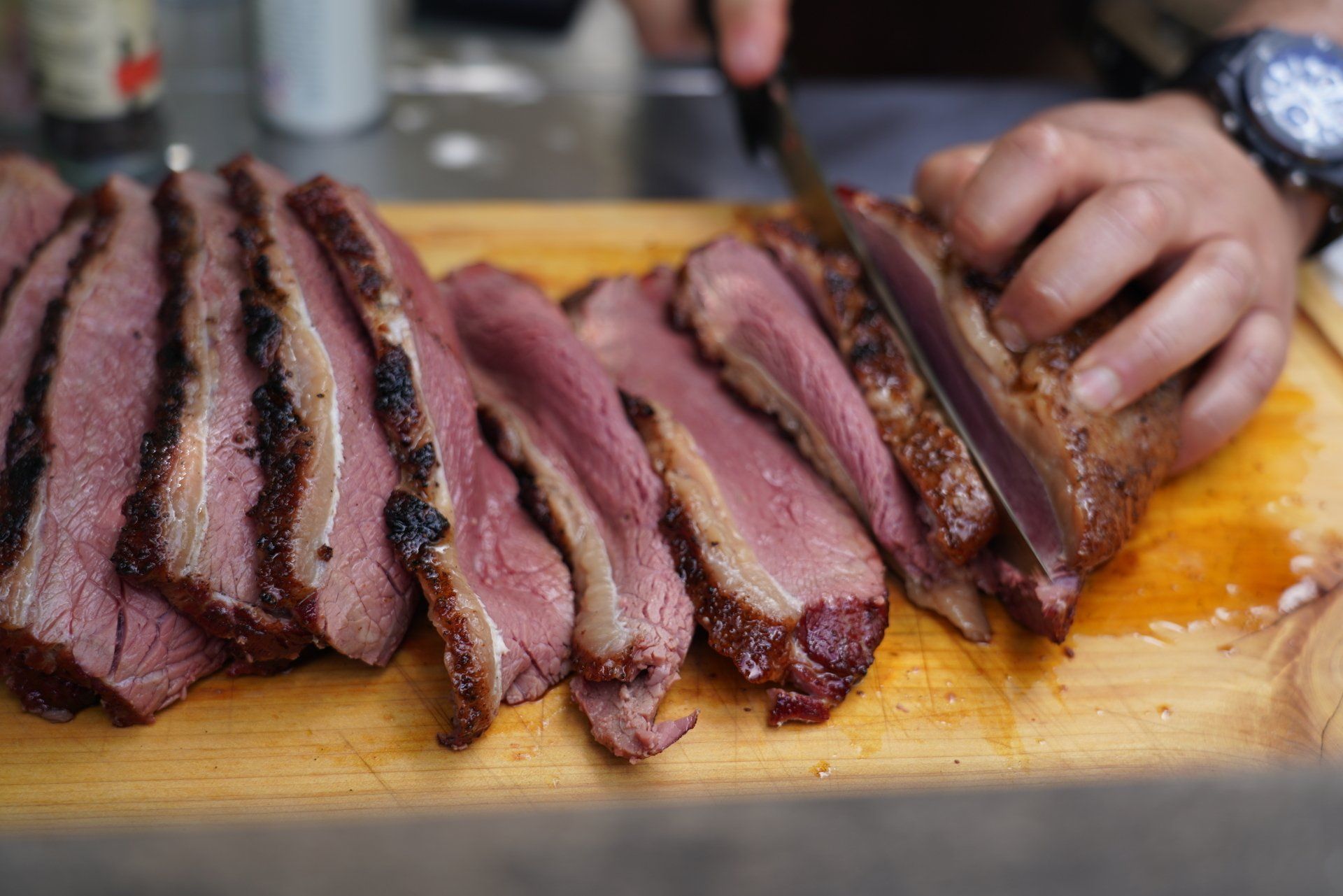 A person is cutting a piece of meat on a cutting board.