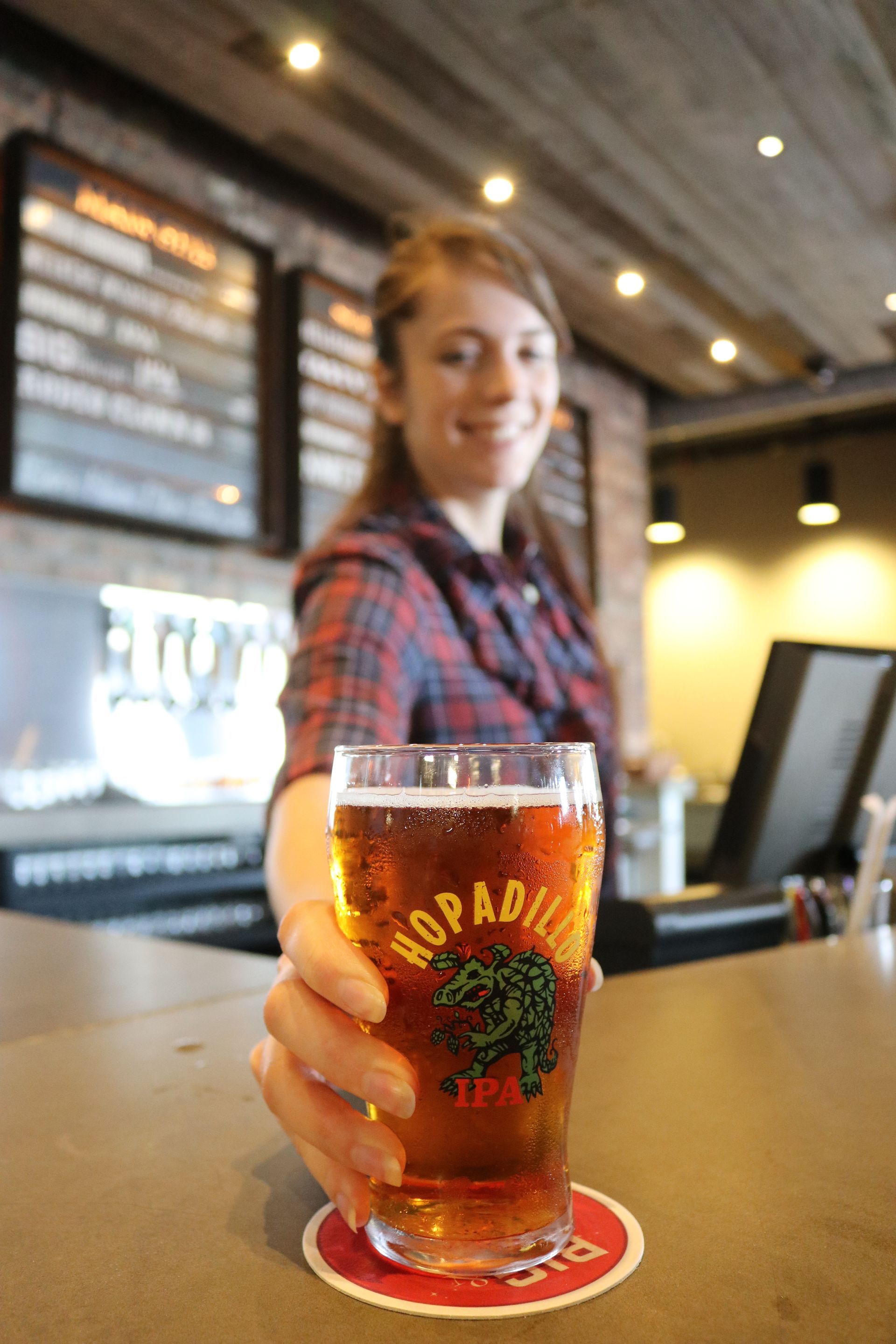 A woman is holding a glass of beer in her hand.