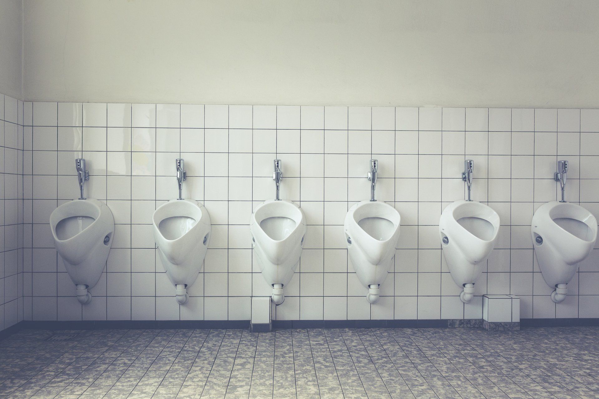 A row of urinals are lined up in a public restroom.