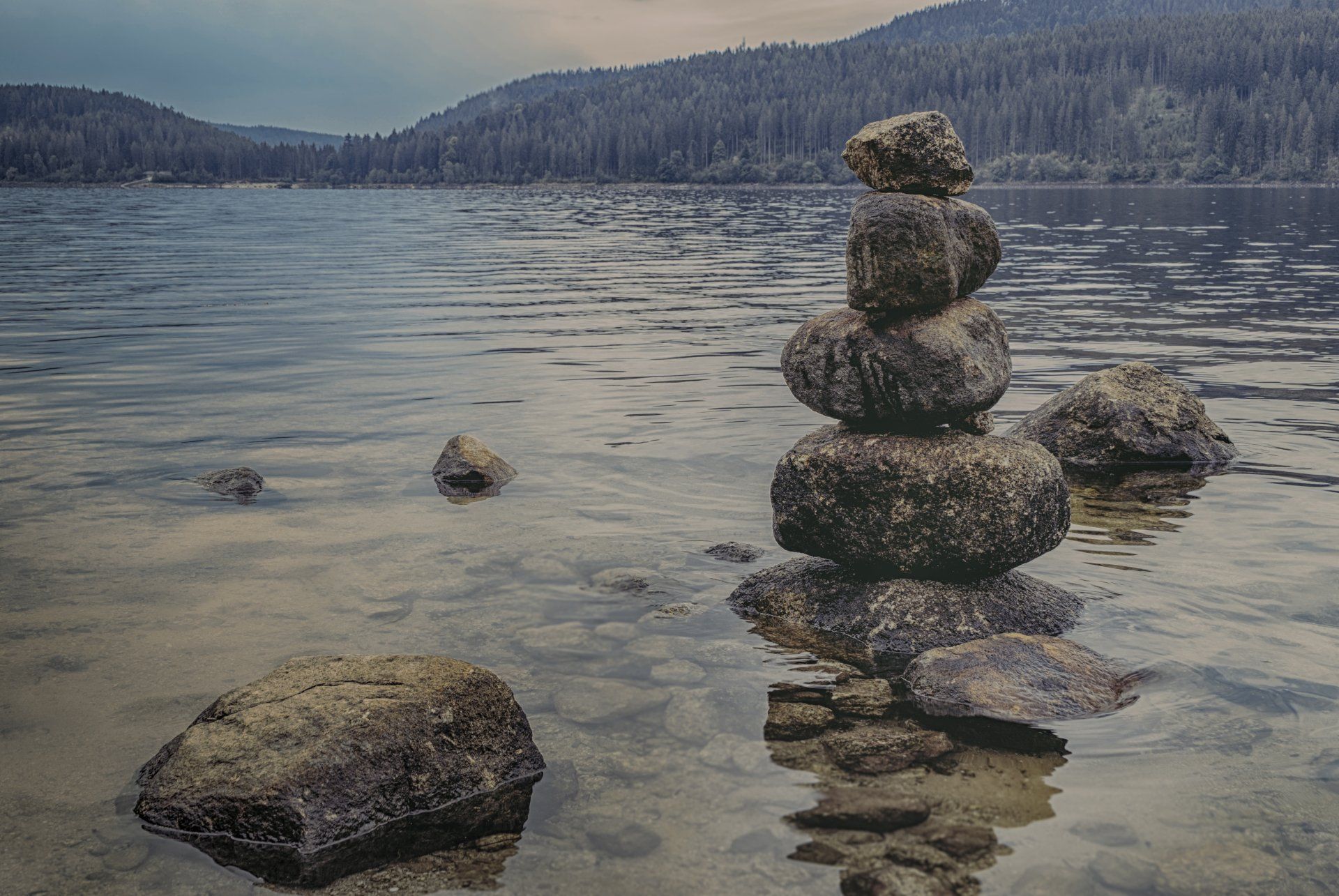 A pile of rocks stacked on top of each other on the shore of a lake.