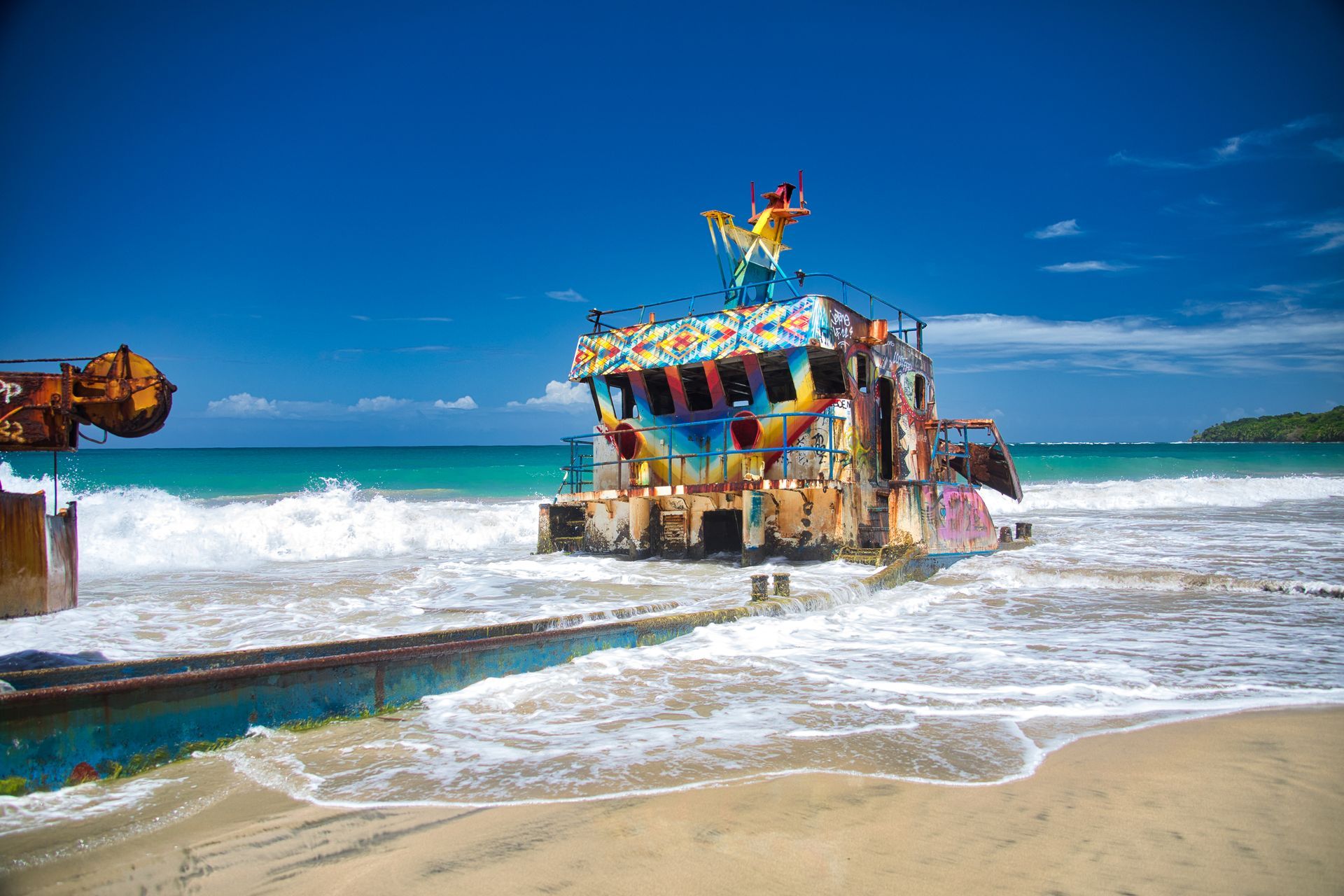 A colorful building is sitting on top of a sandy beach next to the ocean.