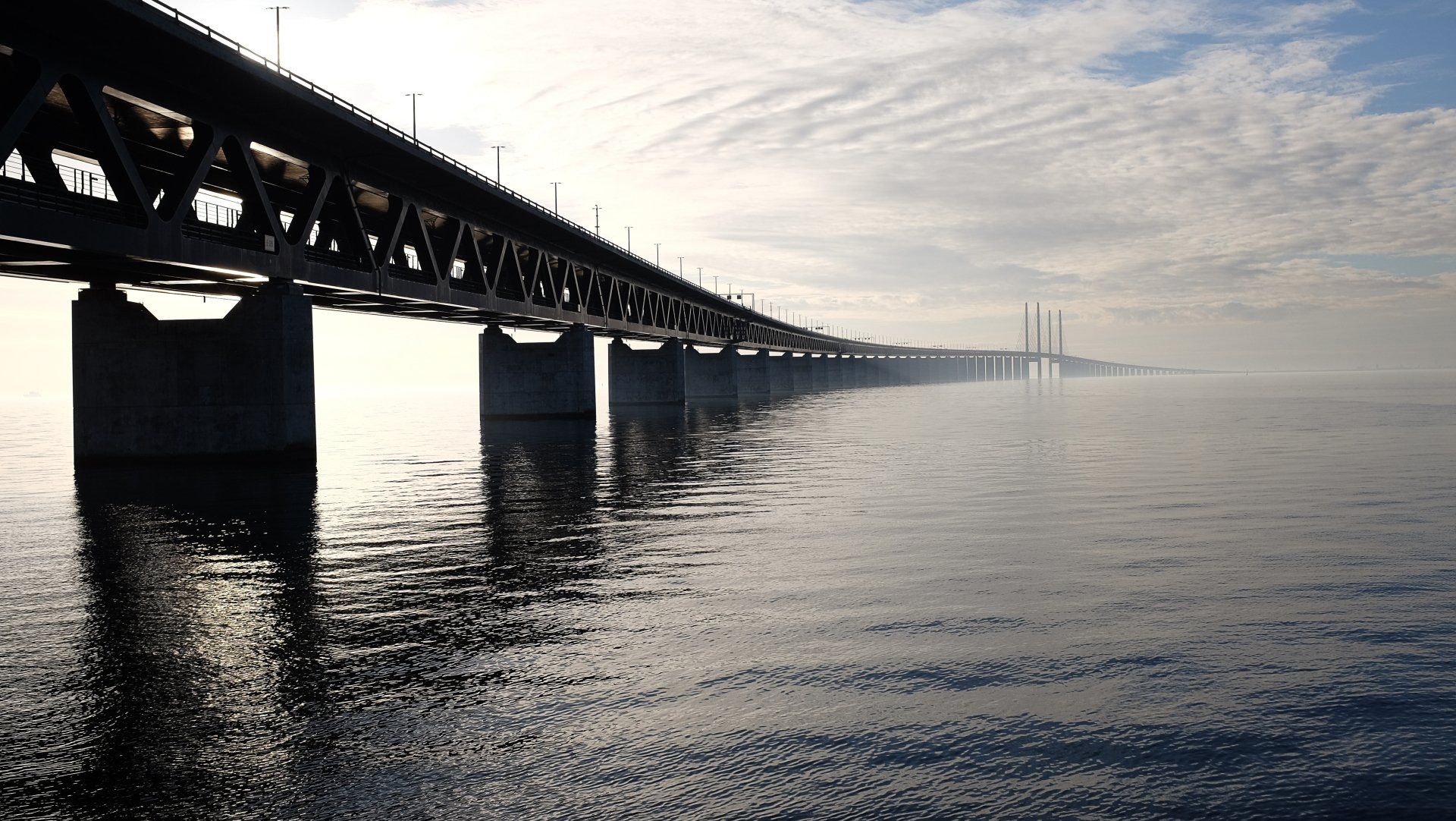 A water bridge showcasing a smooth concrete surface, spanning across a body of water with scenic sur