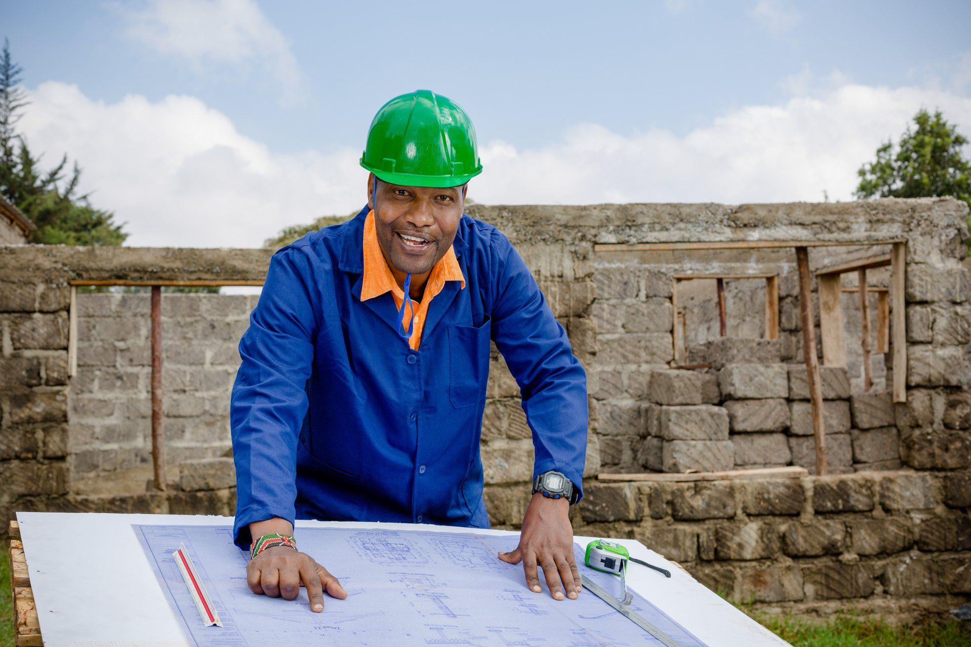 Worker in green hard hat reviewing blueprints at a construction site