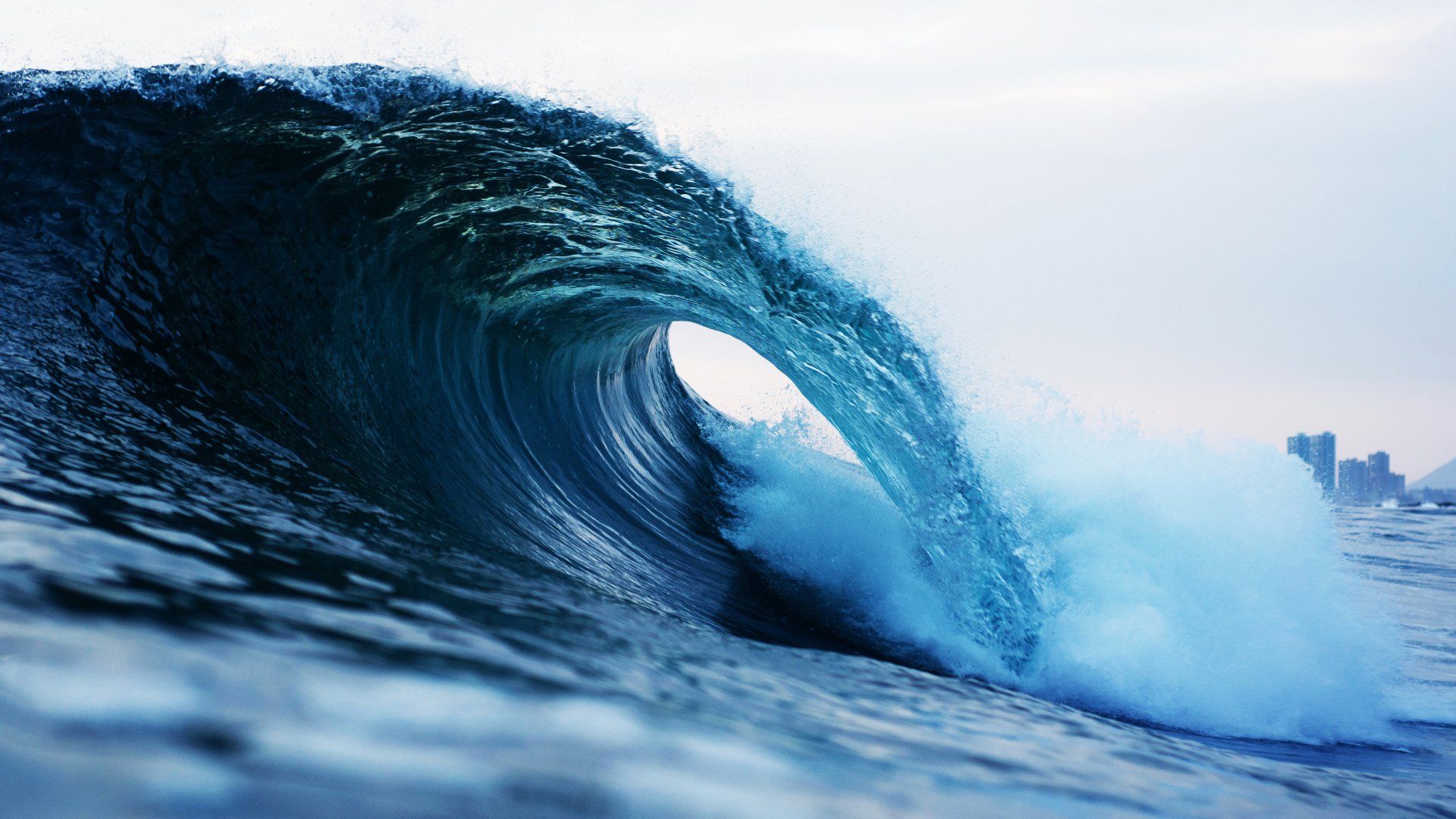 A large wave in the ocean is breaking on the shore.