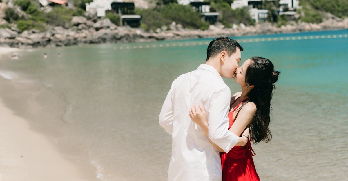 A man and a woman are kissing on the beach.