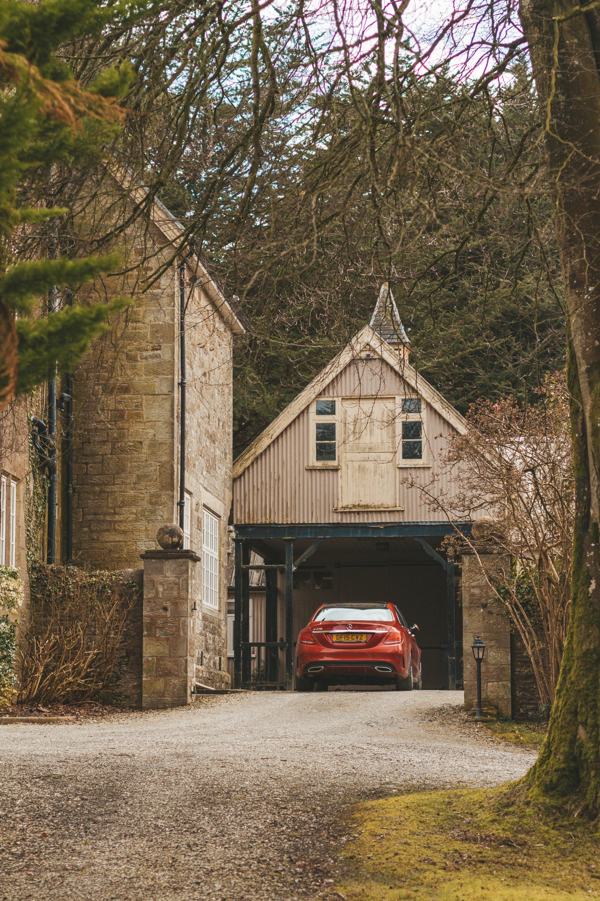 A red car is parked in a garage next to a house.