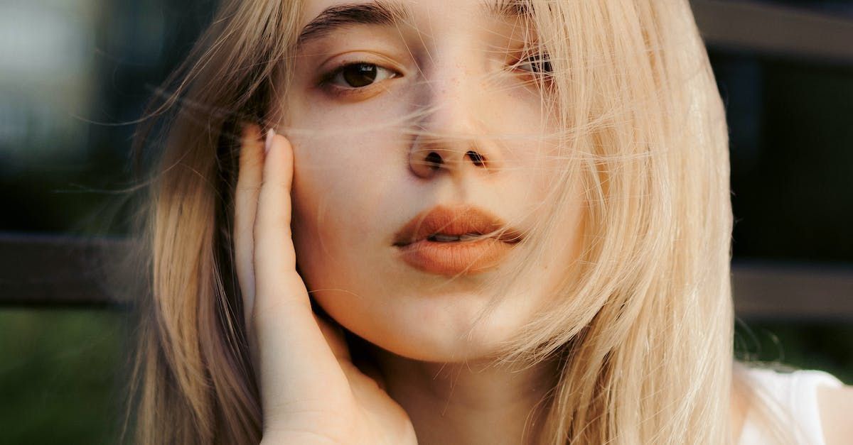 A close up of a woman 's face with her hand on her face.