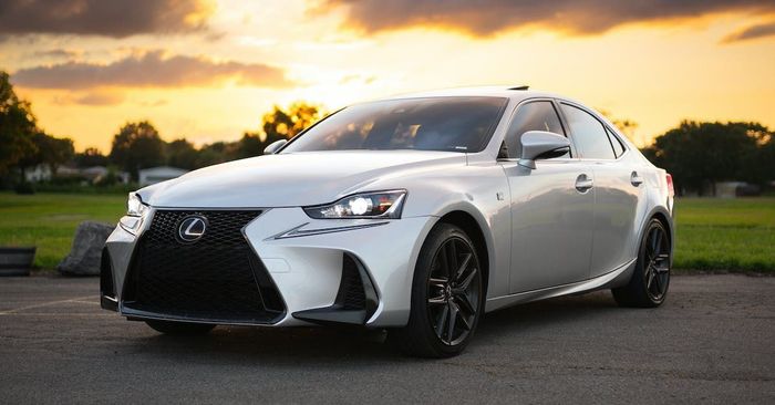 A white lexus is parked in a parking lot at sunset.