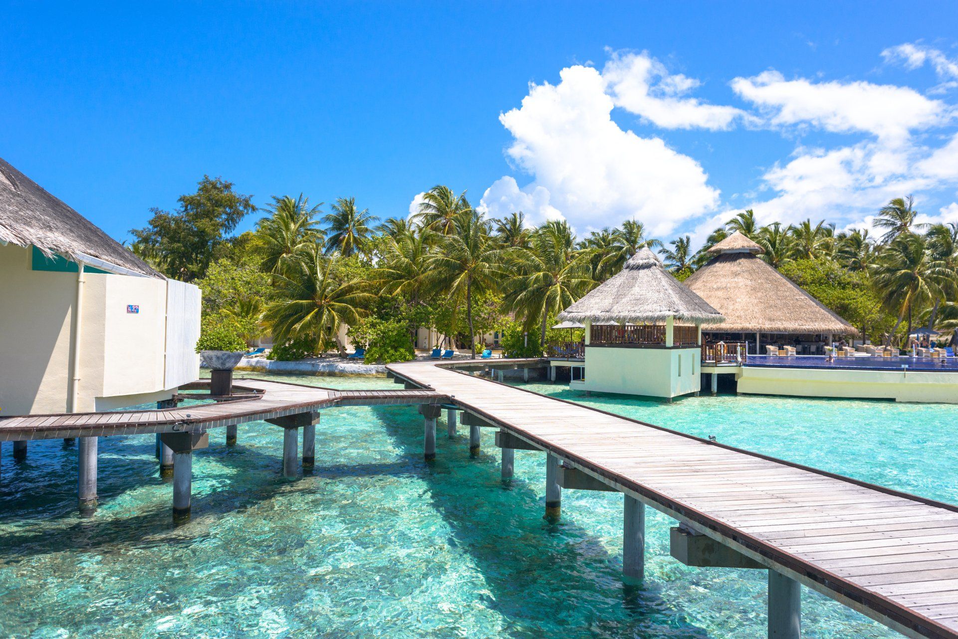A wooden pier leading to a house in the middle of the ocean.