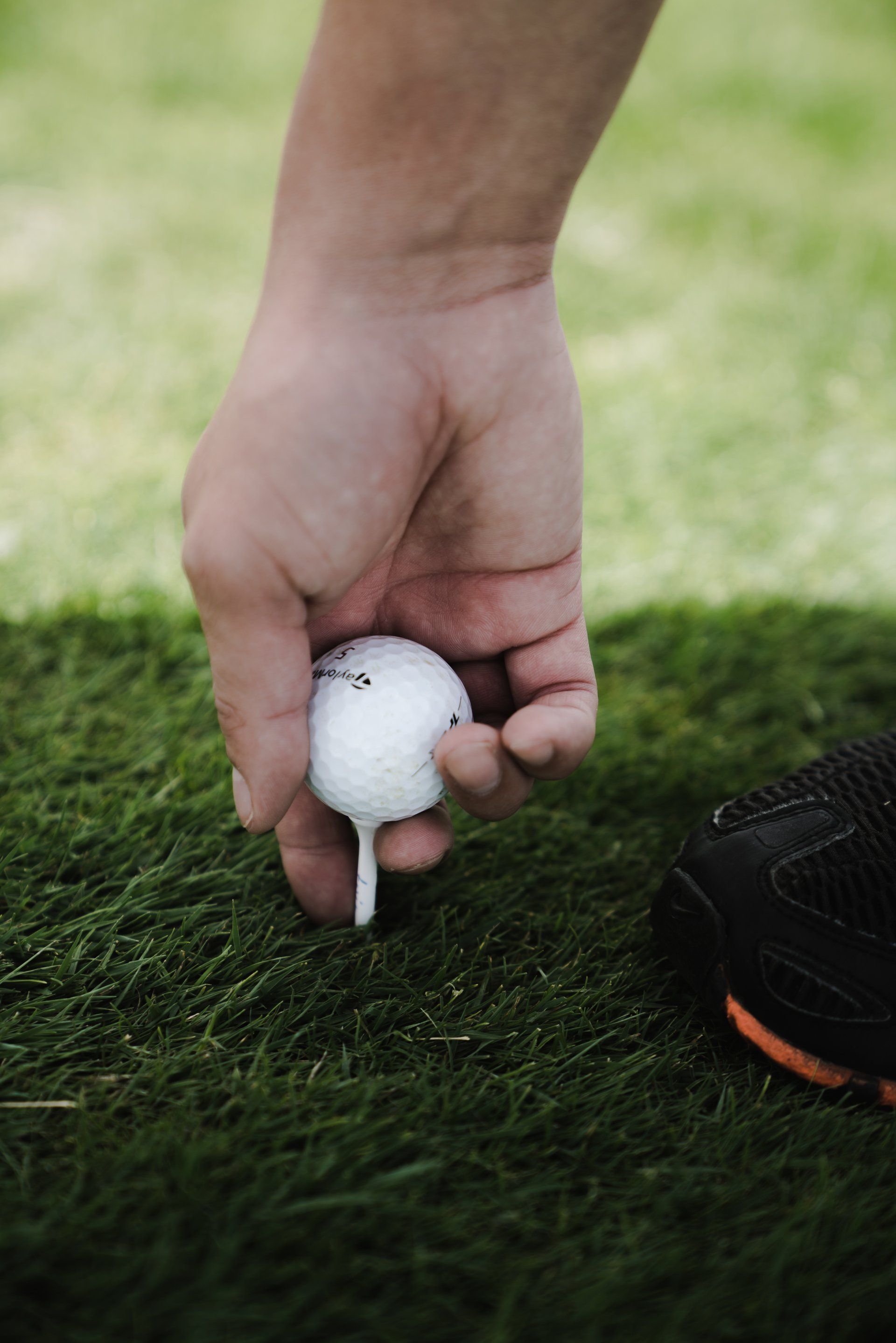 A person is putting a golf ball on a tee.