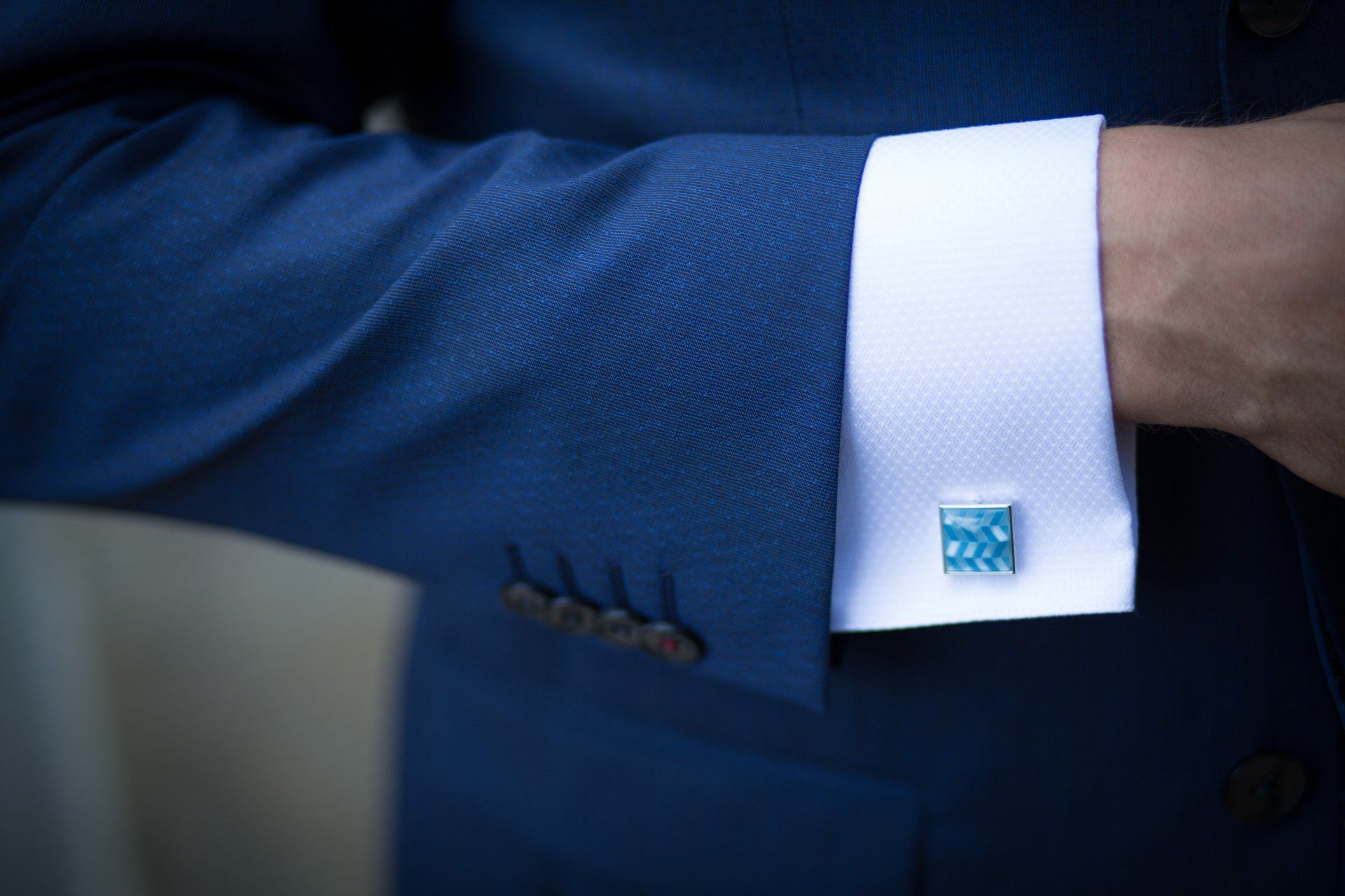 A man wearing a blue suit and white cufflinks.