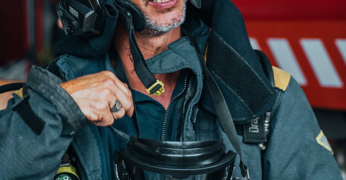 A man in a firefighter 's uniform is putting on a gas mask.