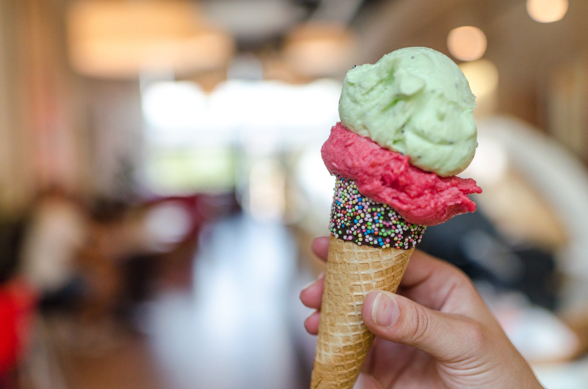 A person is holding an ice cream cone with two different flavors of ice cream.