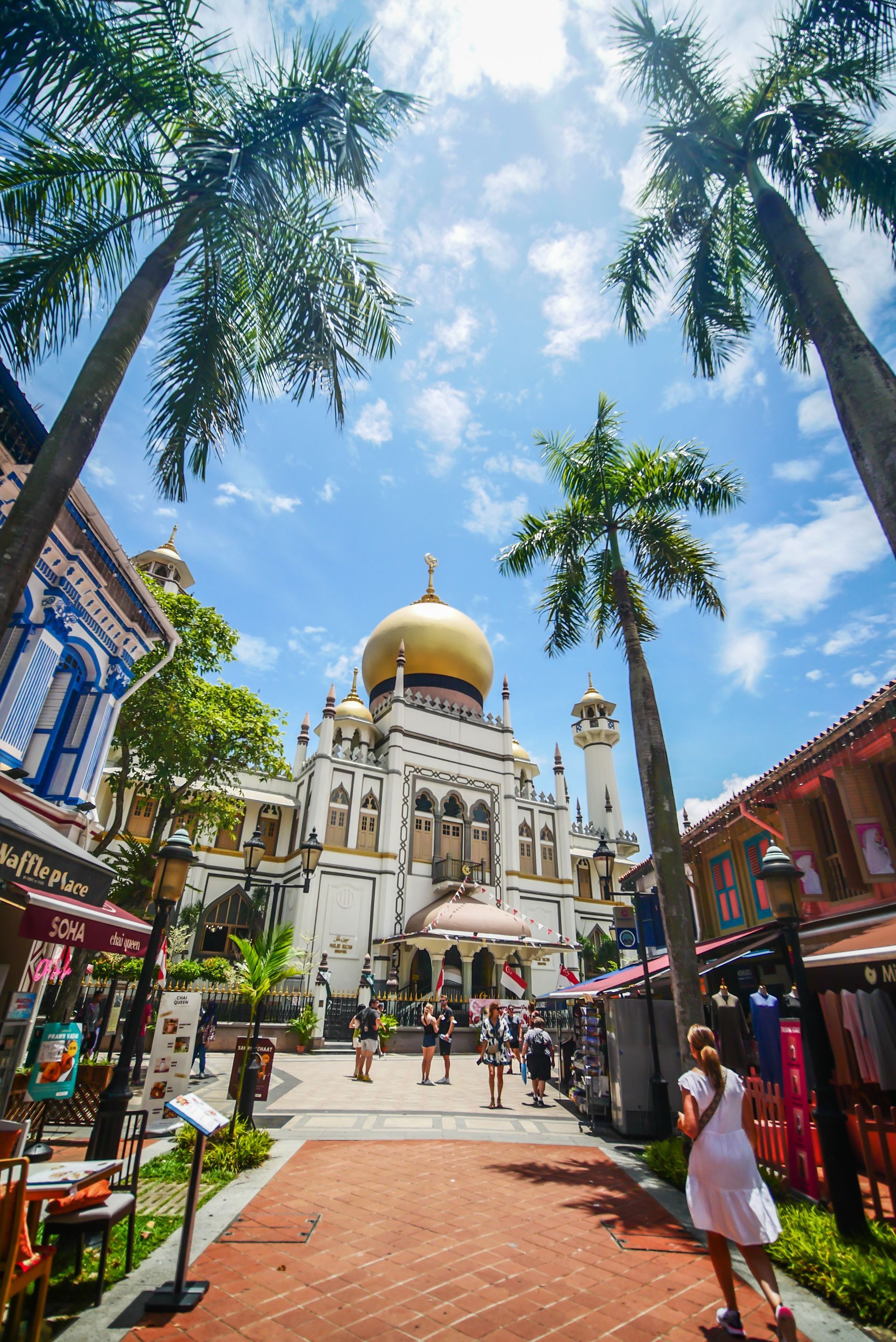 A woman is walking down a sidewalk in front of a mosque.
