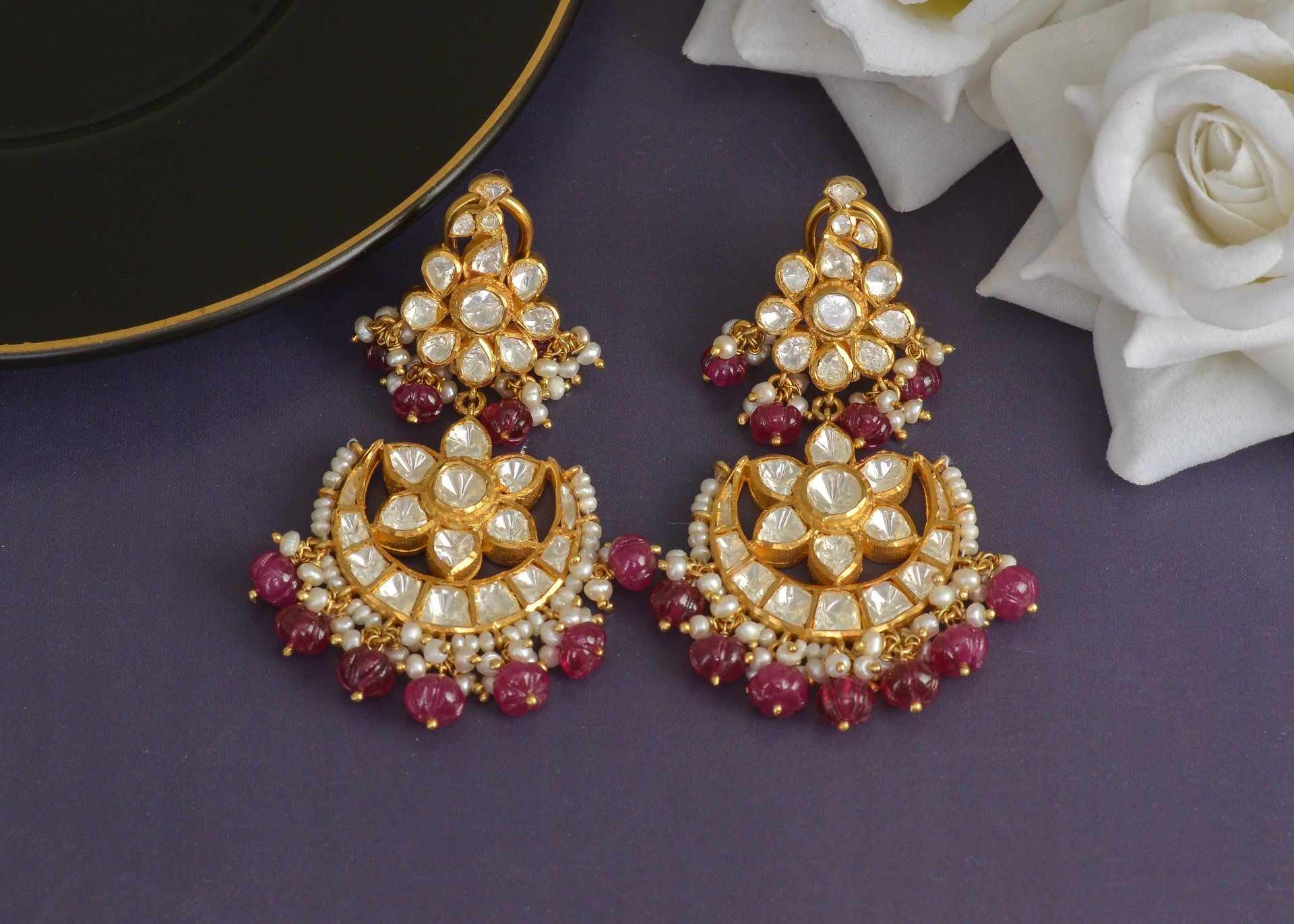 A pair of earrings sitting on a table next to a rose