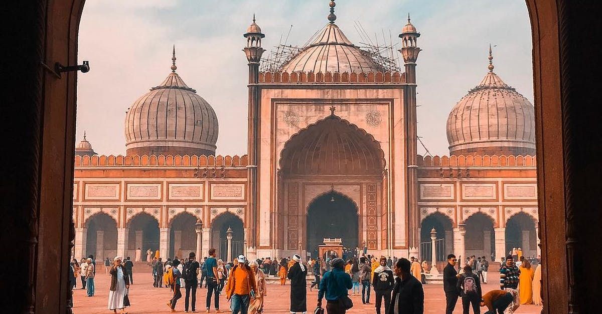 View through an archway of the Jama Masjid in Delhi, with crowds walking across the courtyard in front of the mosque.