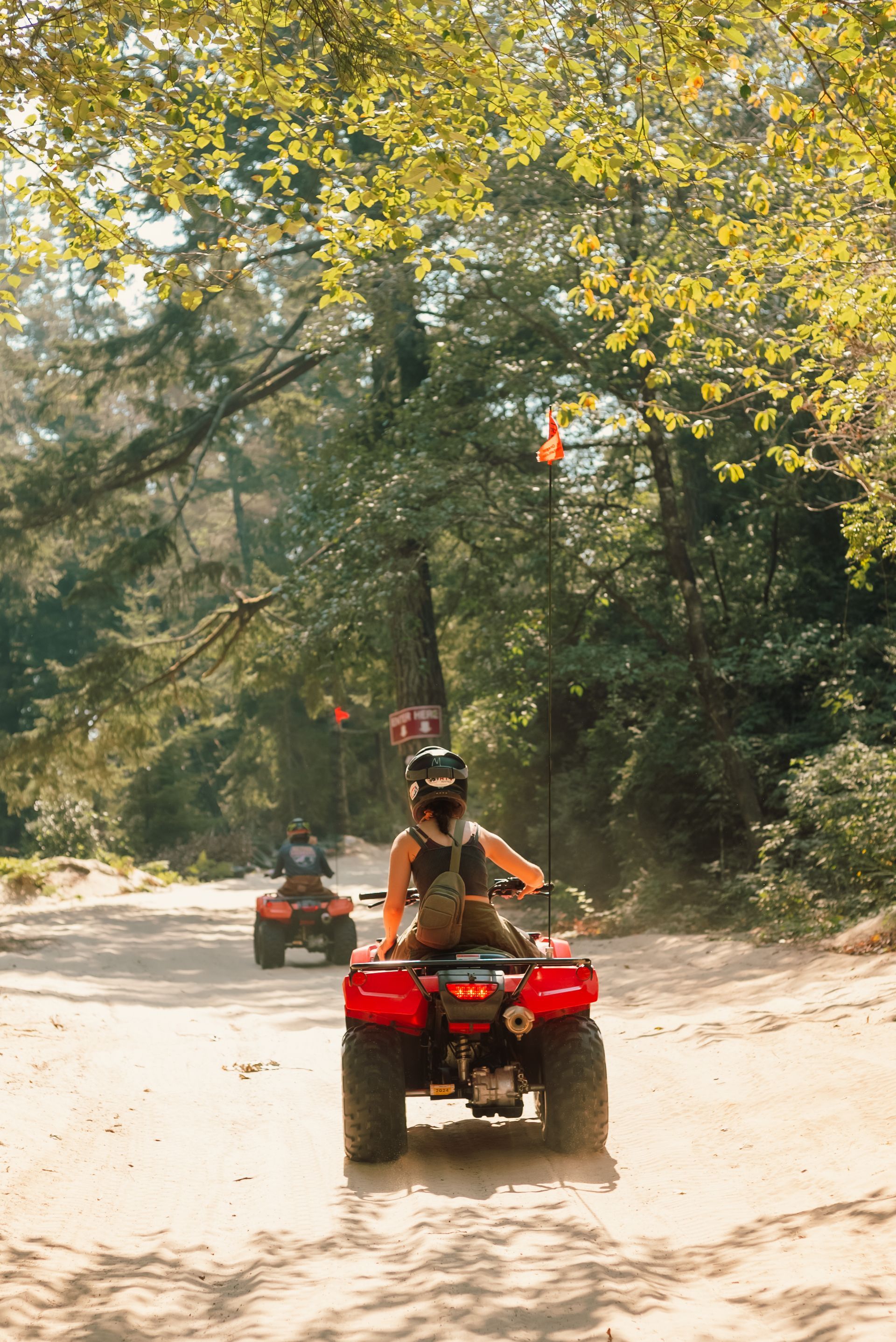 A group of people are riding atvs down a dirt road.