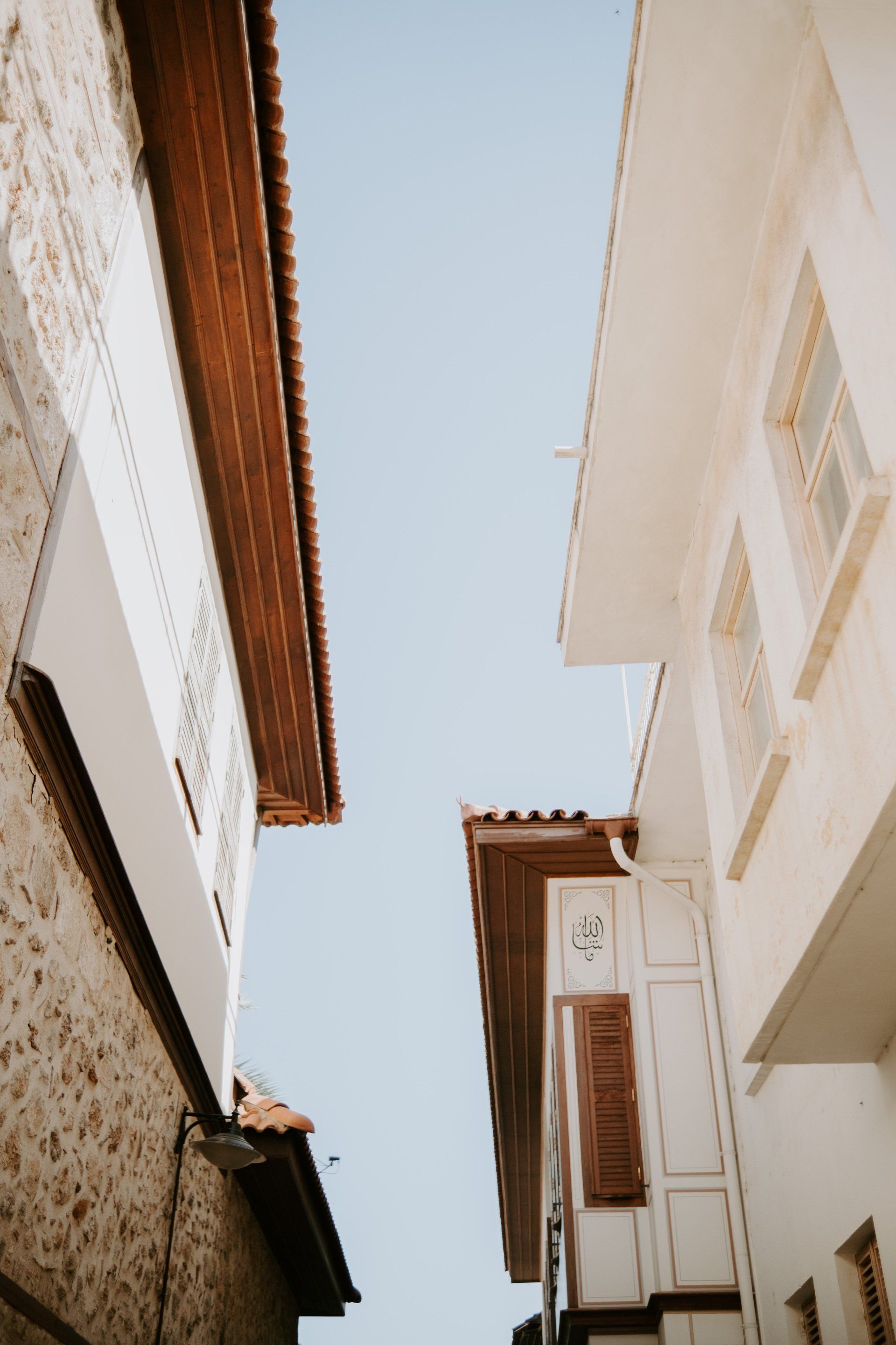Looking up at the roofs of two buildings against a blue sky.