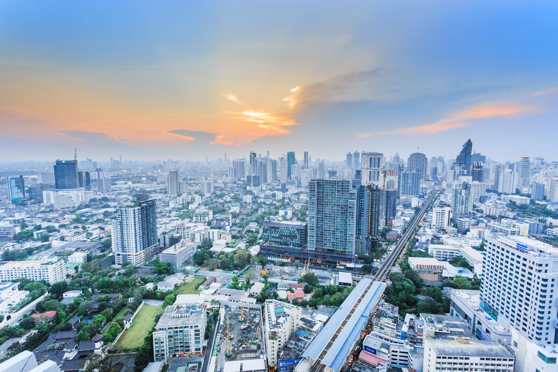An aerial view of a city at sunset with lots of buildings and trees.