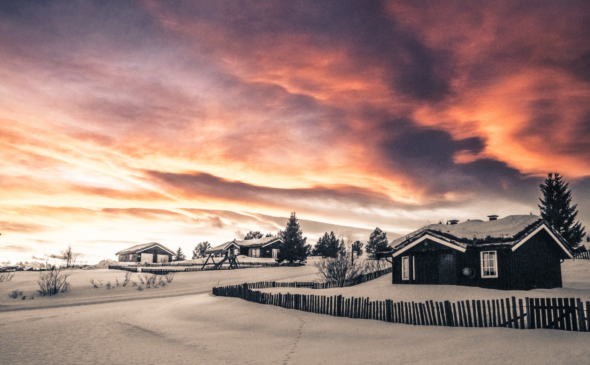 una casa nella neve con un tramonto sullo sfondo