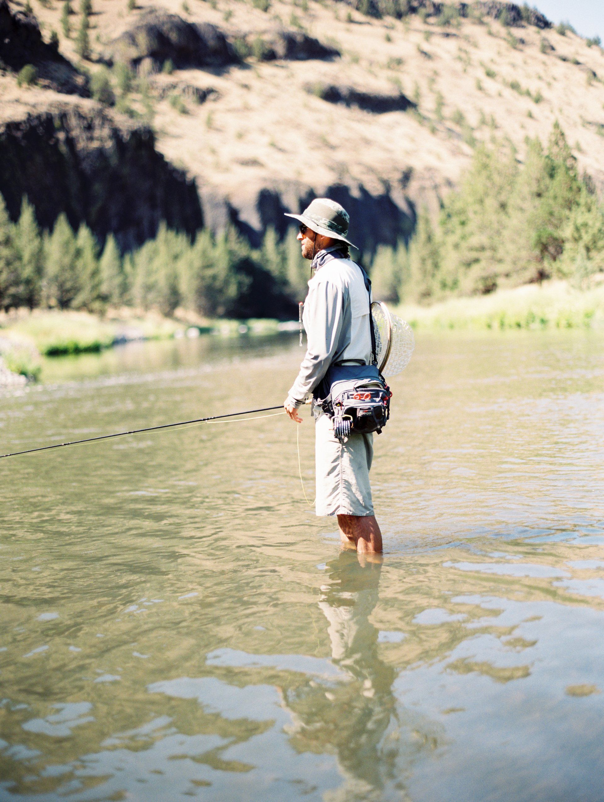 A person fly fishing in a lake.