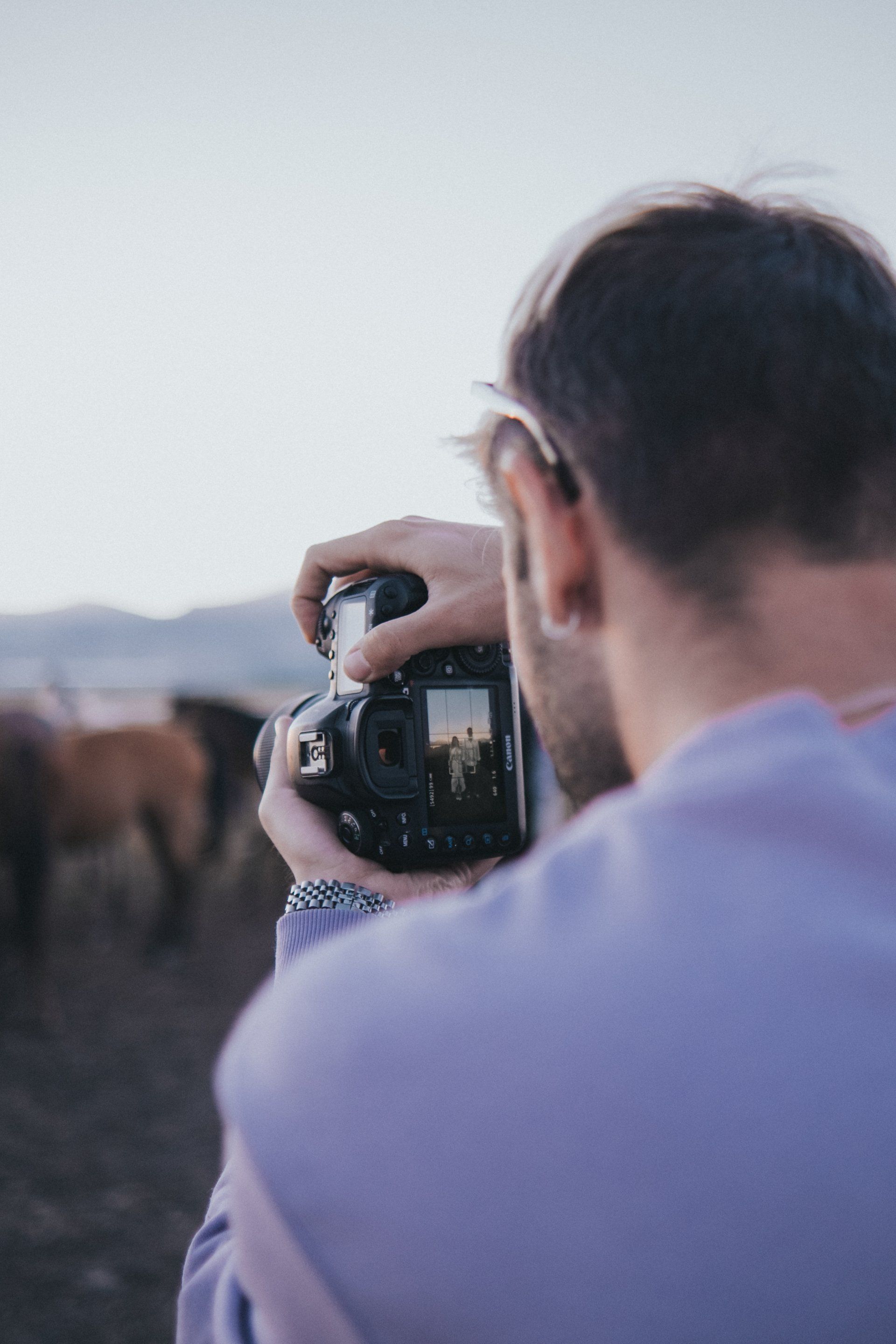 A man is taking a picture of a herd of horses with a camera.