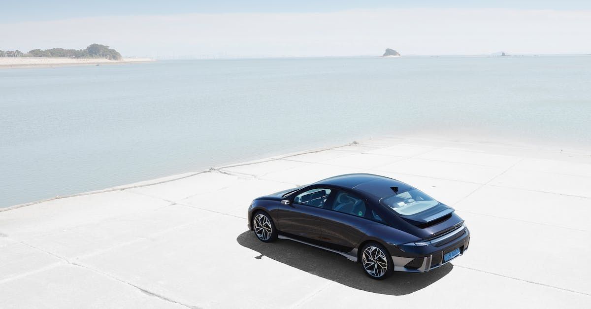 A blue car is parked on the beach next to the ocean.