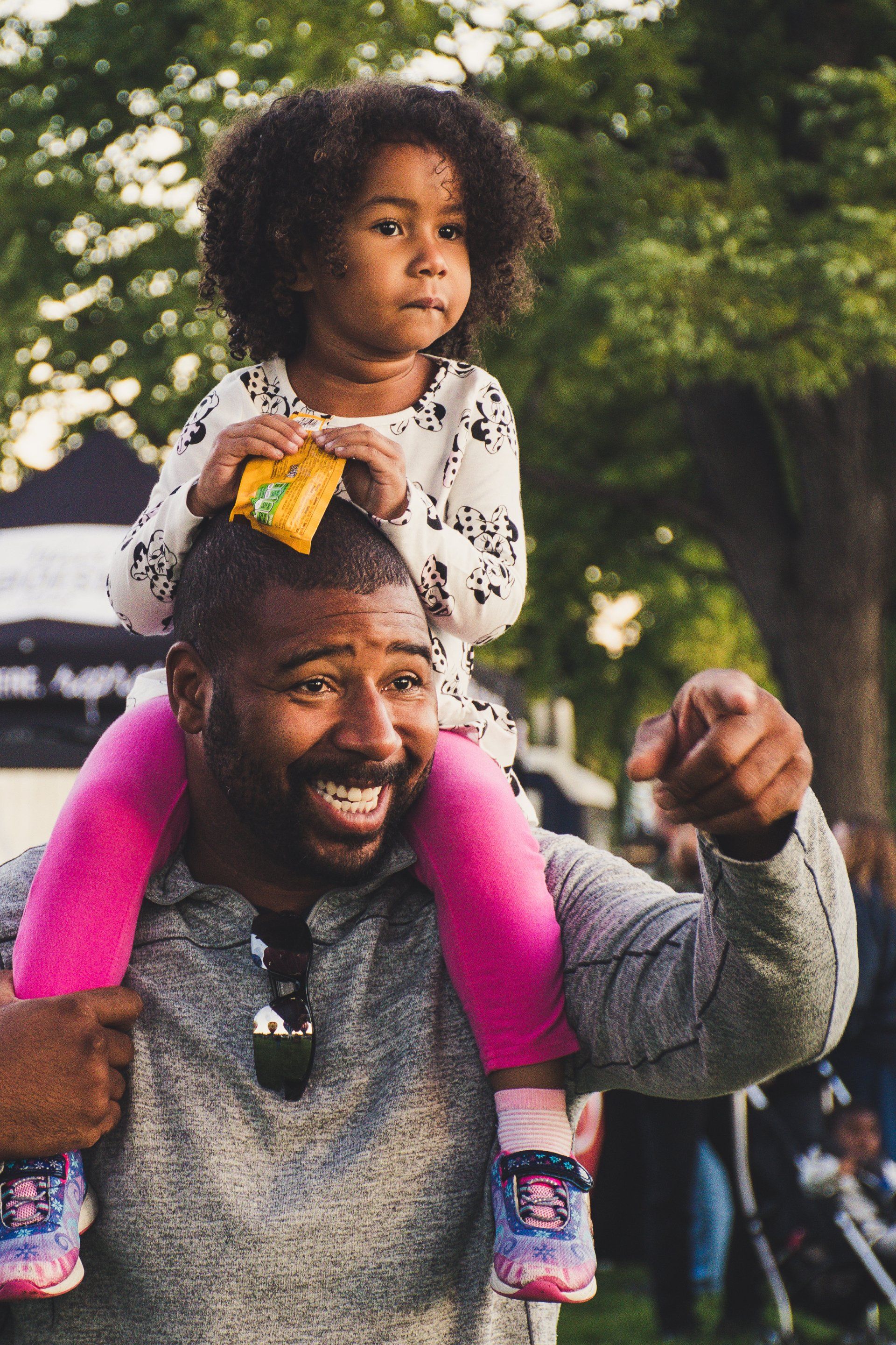 A man is carrying a little girl on his shoulders.
