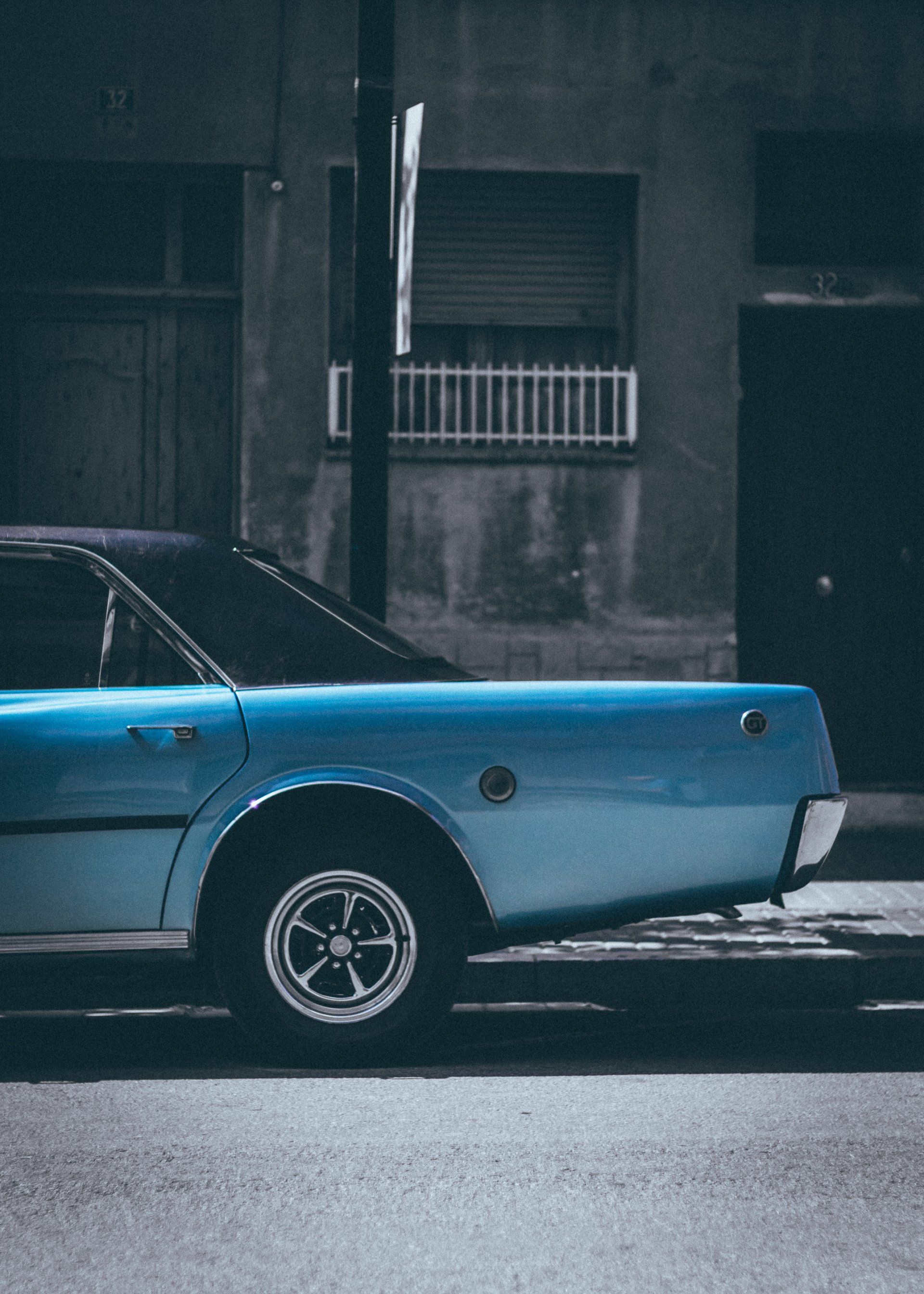 A blue car is parked on the side of the road.