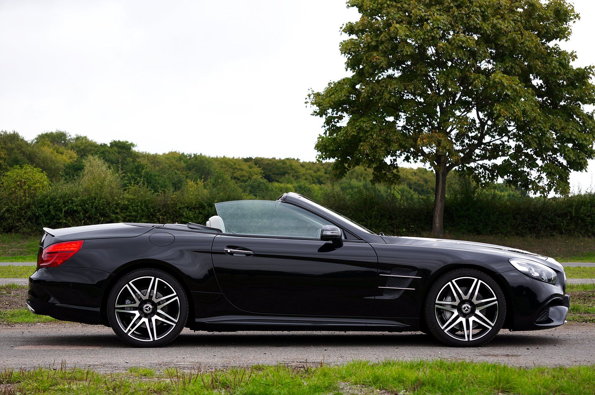 A black convertible is parked in a grassy field