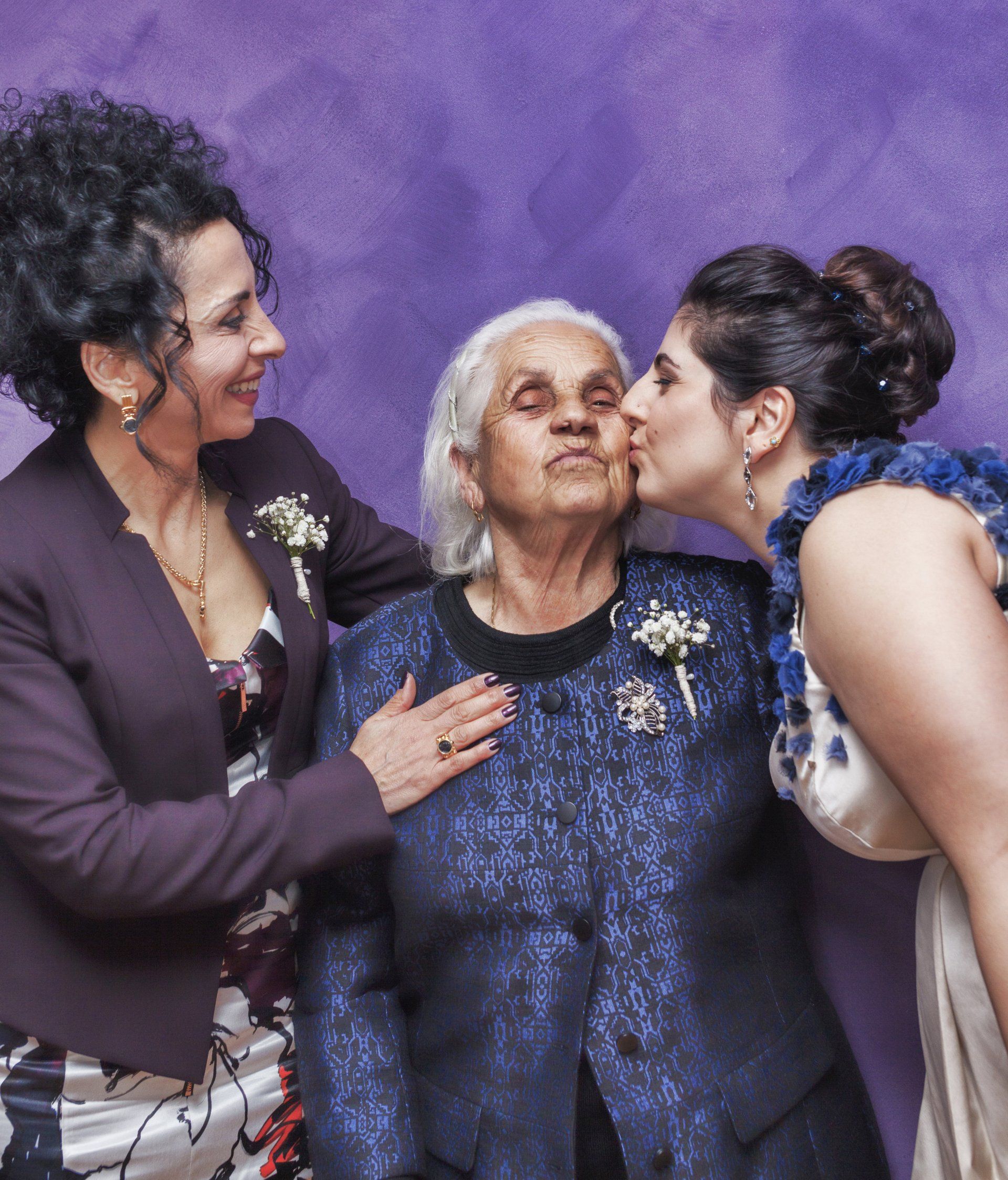 Two women are kissing an older woman on the cheek