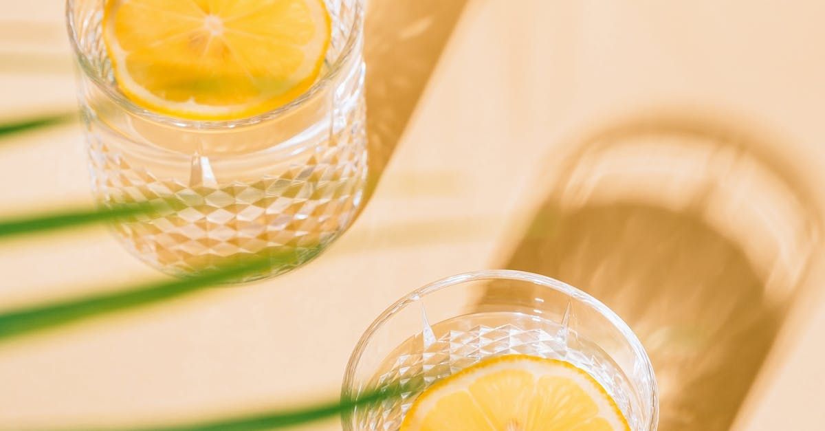Two glasses of water with lemon slices on a table.