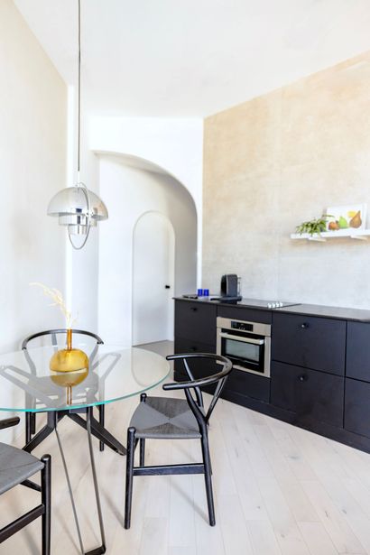 A kitchen with black cabinets and a glass table and chairs