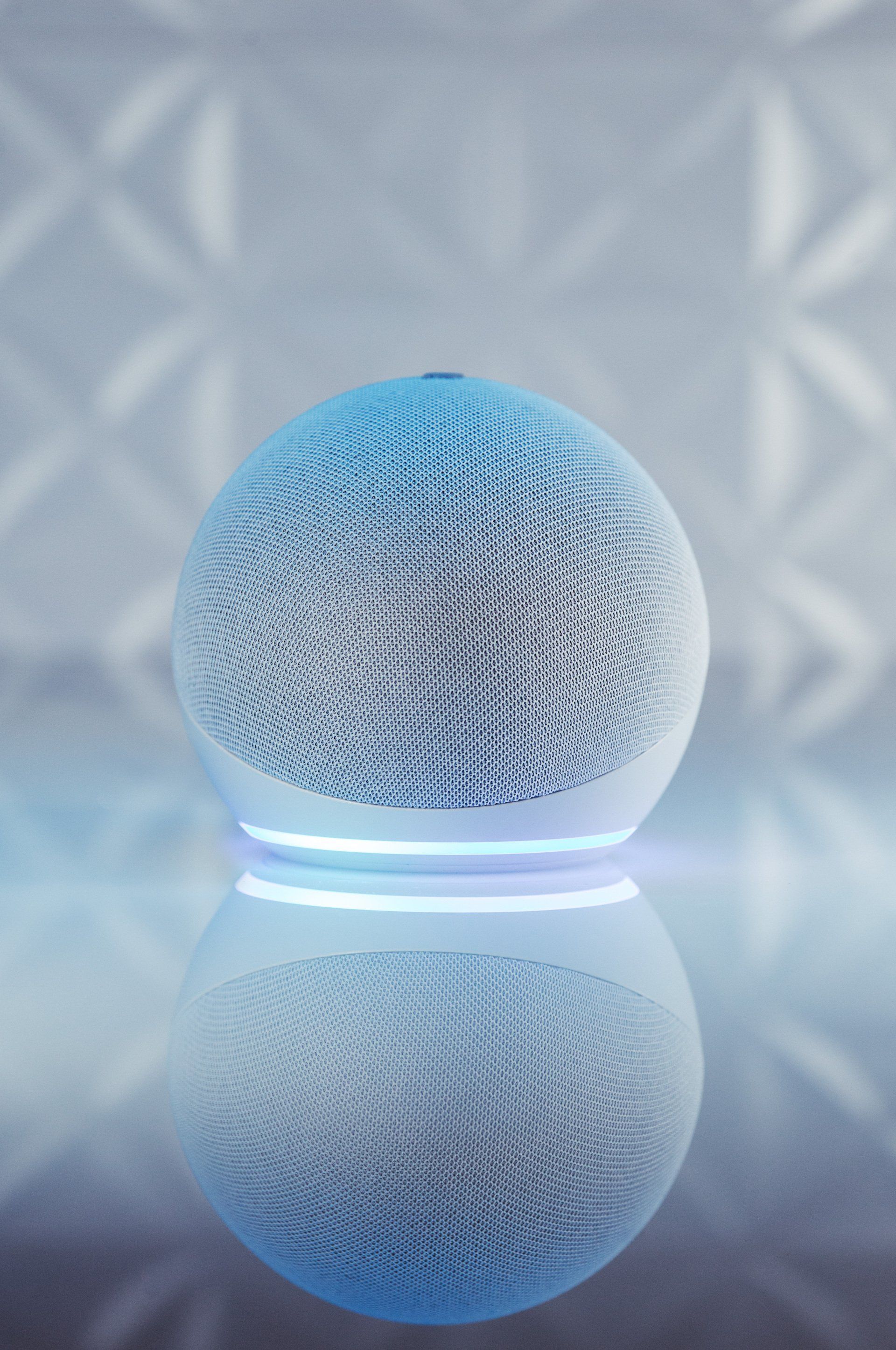 Uma esfera branca com uma luz azul está sobre uma mesa.