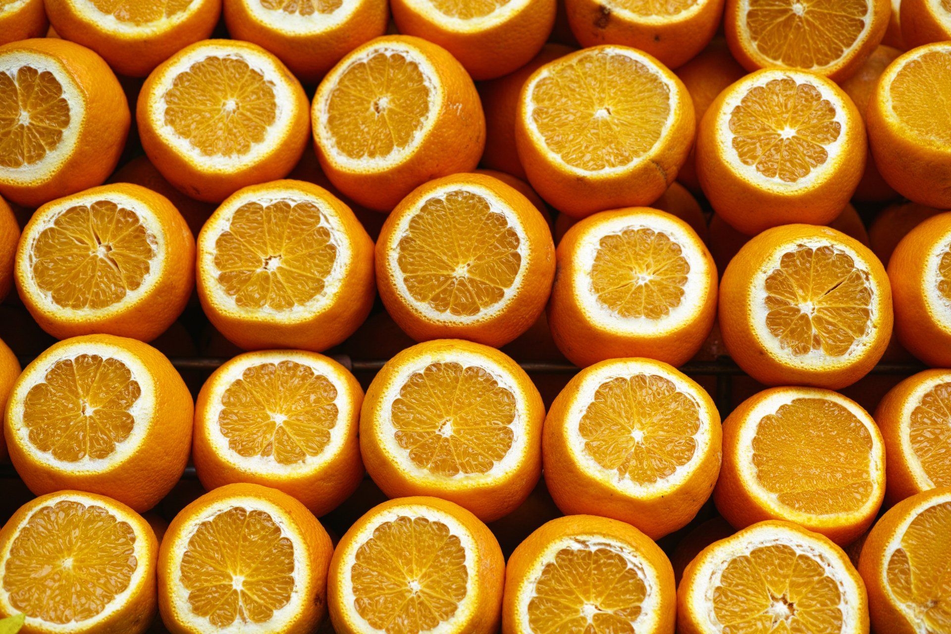 Reihen von aufgeschnittenen Orangen, deren saftiges Inneres sichtbar ist.