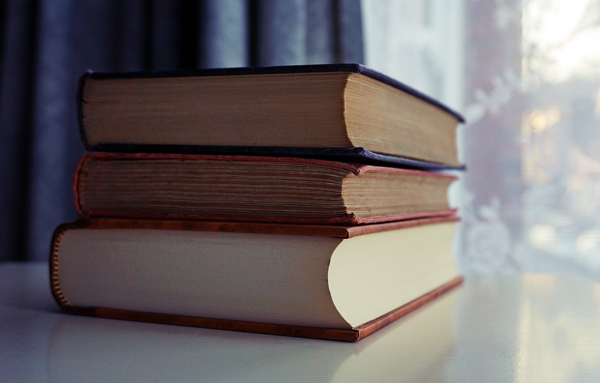 Three books are stacked on top of each other on a table.